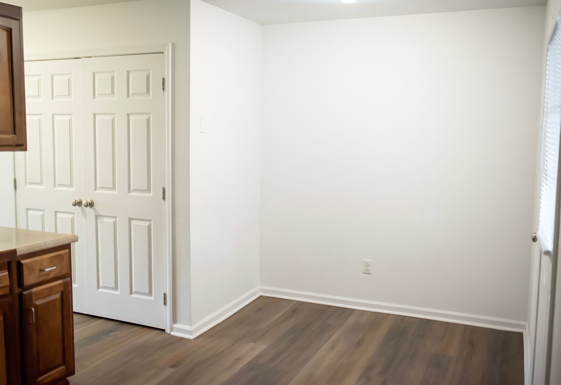 An empty room with hardwood floors and white walls in a house.
