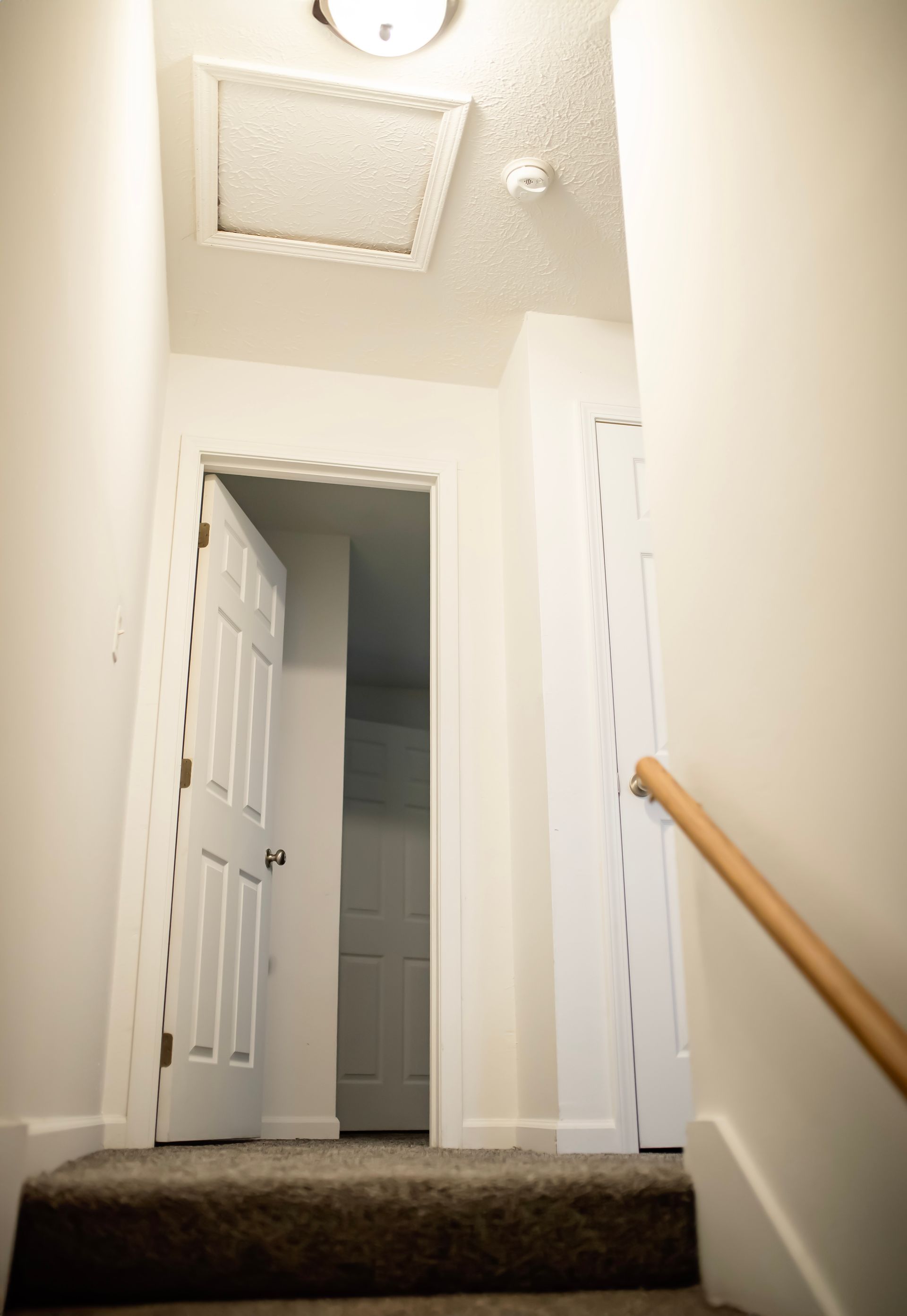 A staircase with a wooden railing leading up to a door.