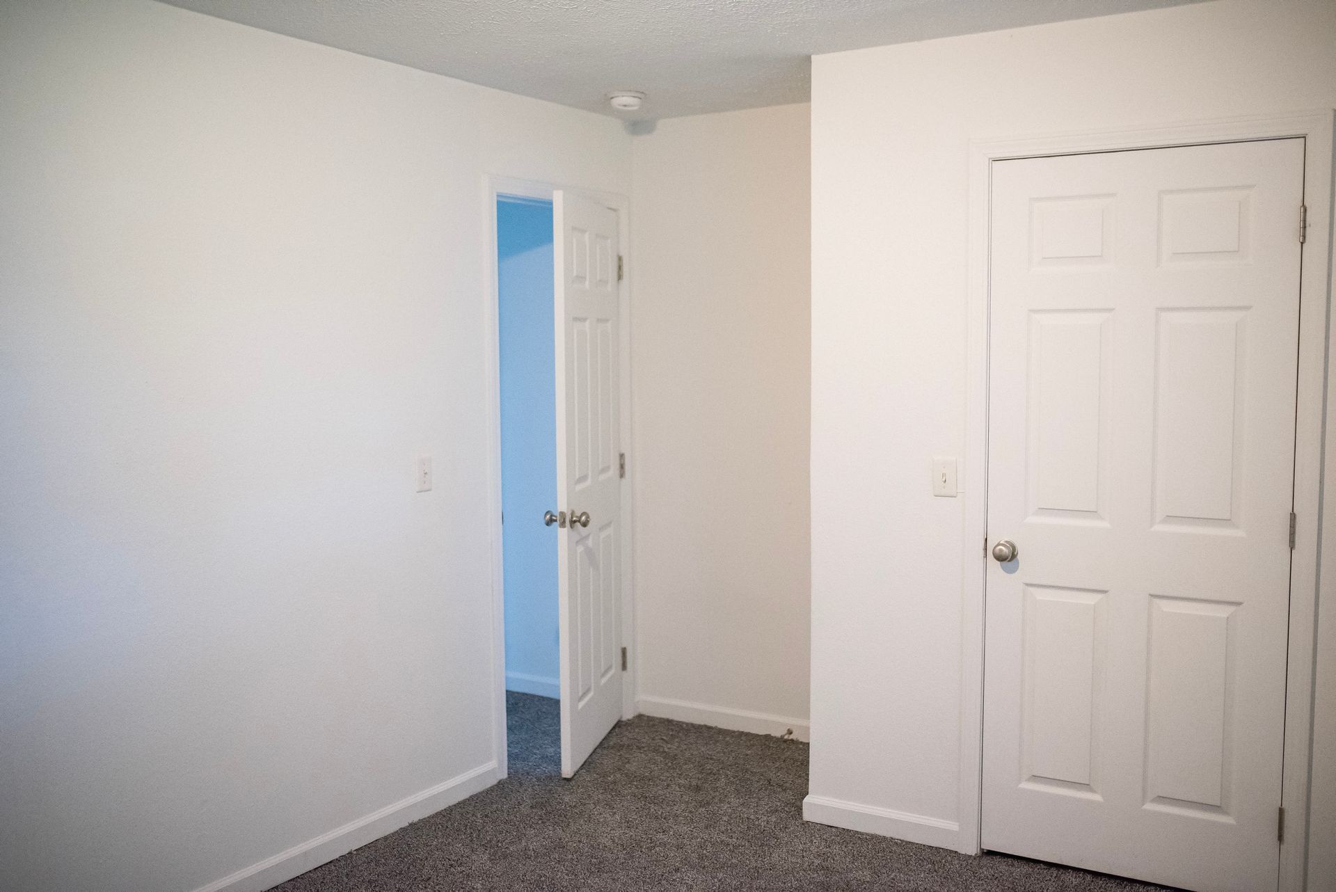 An empty bedroom with a closet and a door.