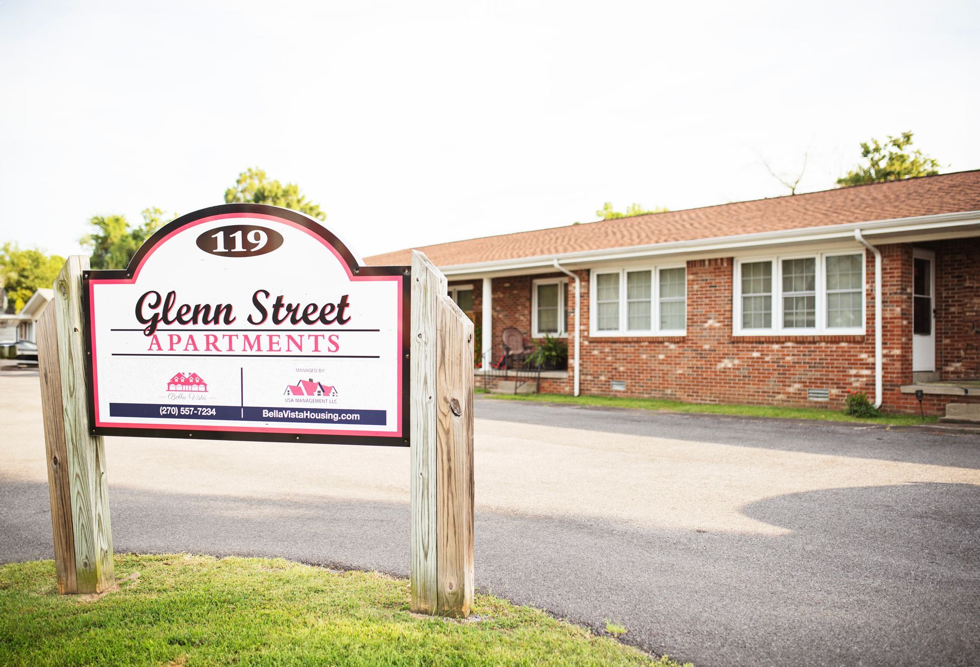 A sign for glenn street apartments is in front of a brick building.