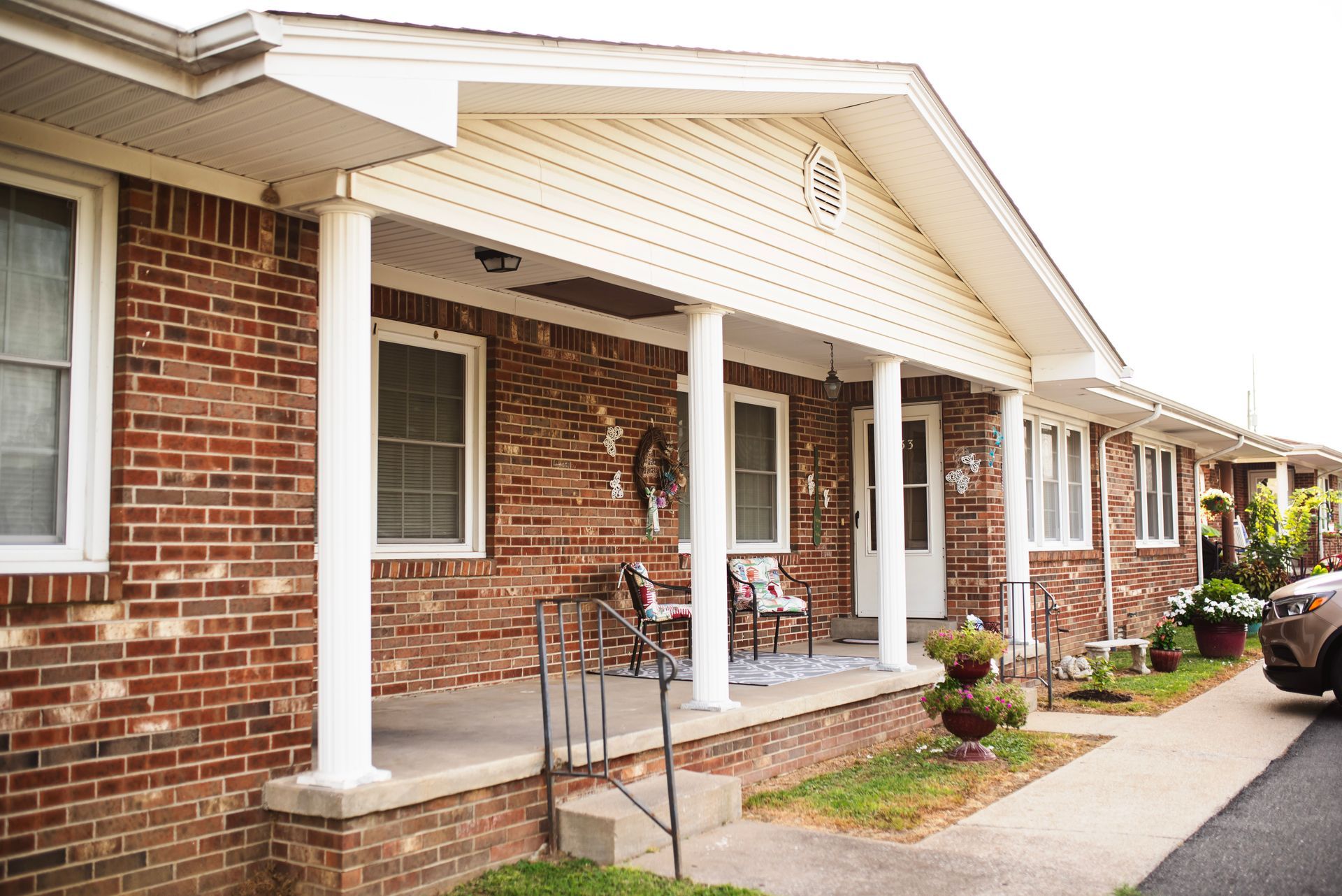 A brick house with a porch and a car parked in front of it.