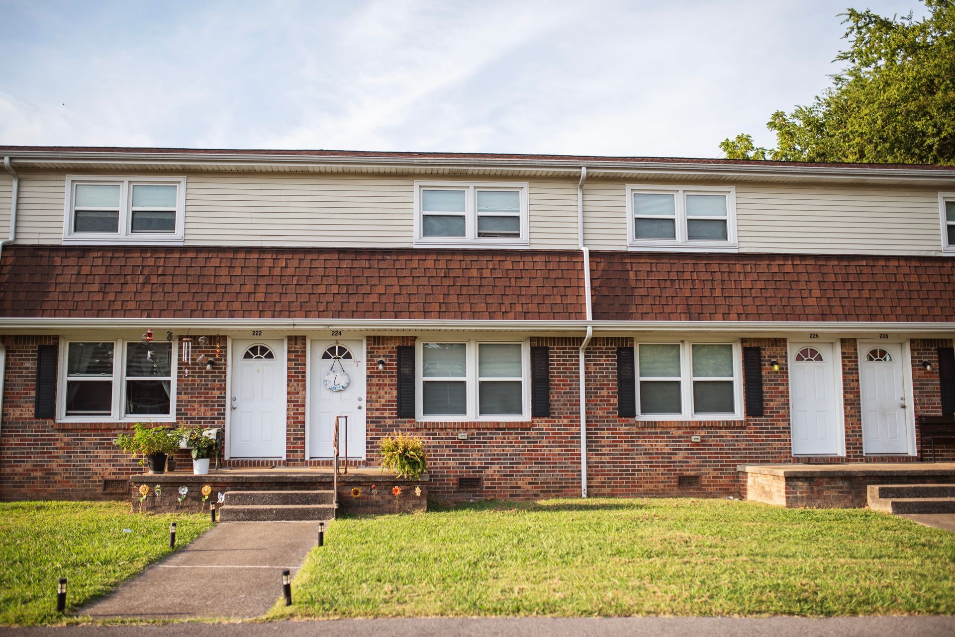 A brick apartment building with white siding and black shutters