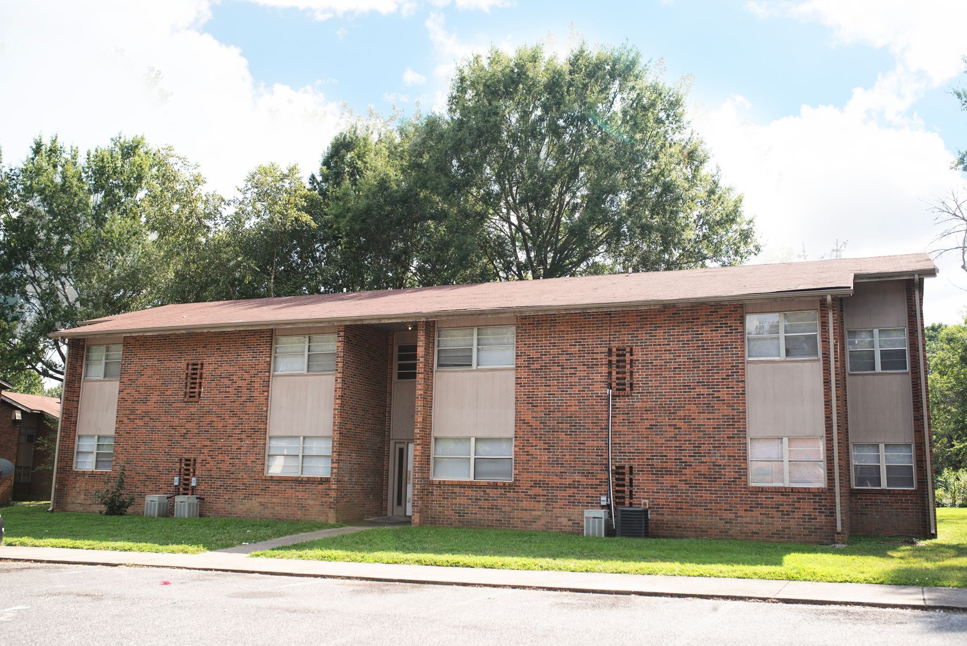 A brick apartment building with trees in the background