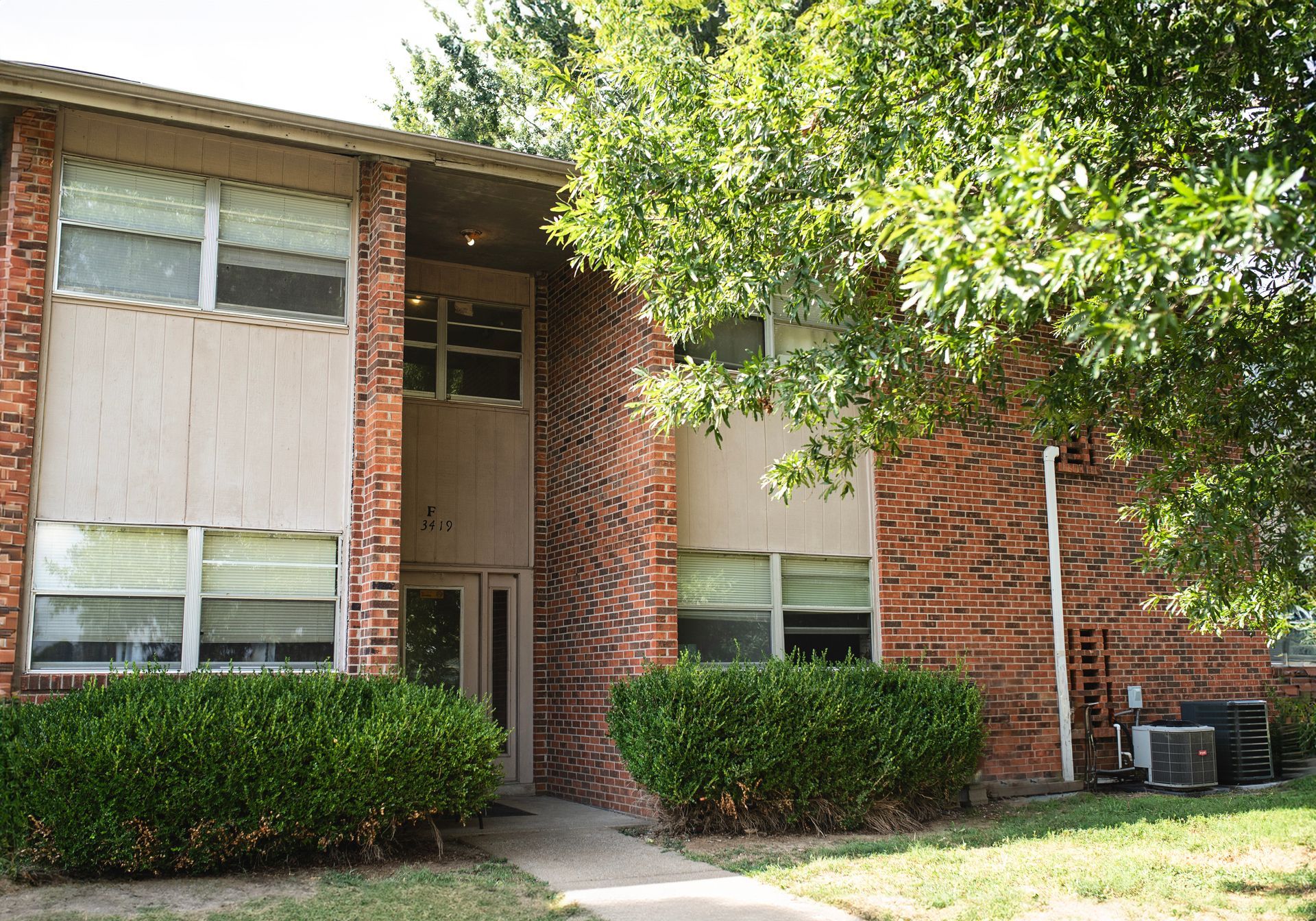 A brick apartment building with a tree in front of it