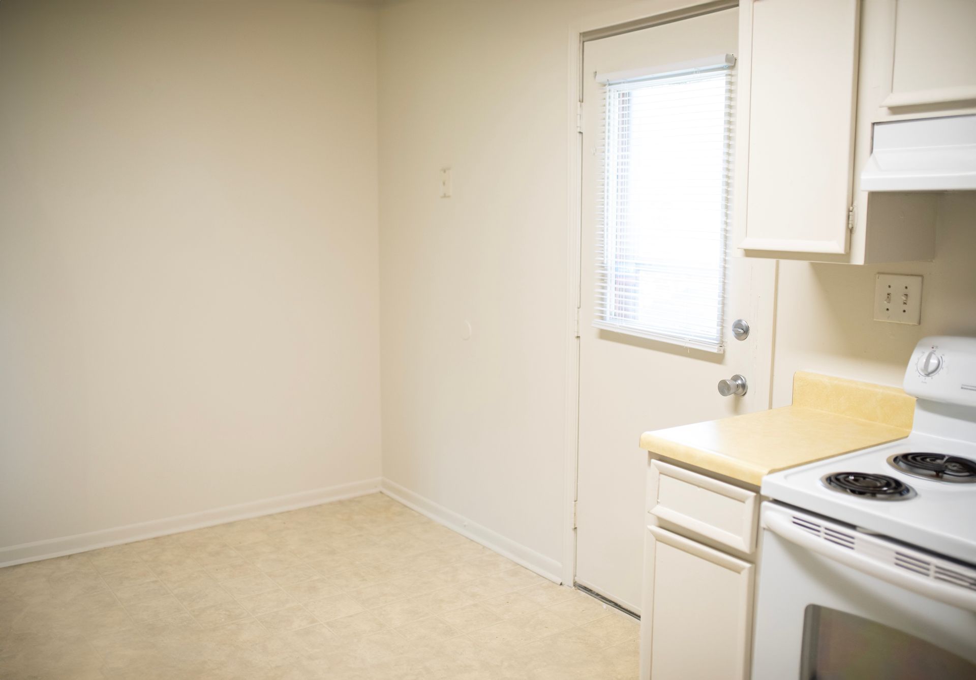 An empty kitchen with a stove and a window