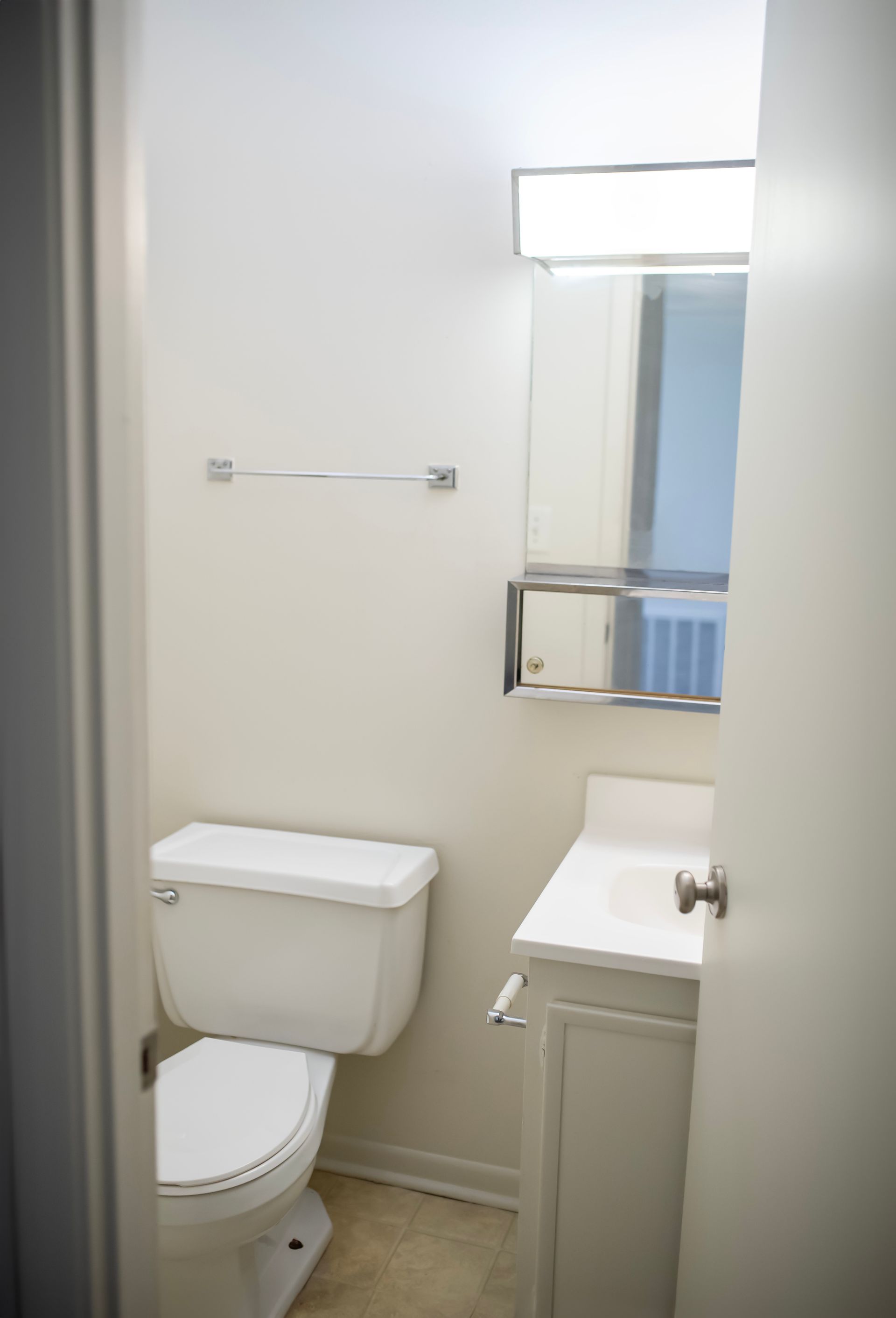 A bathroom with a toilet , sink and mirror.