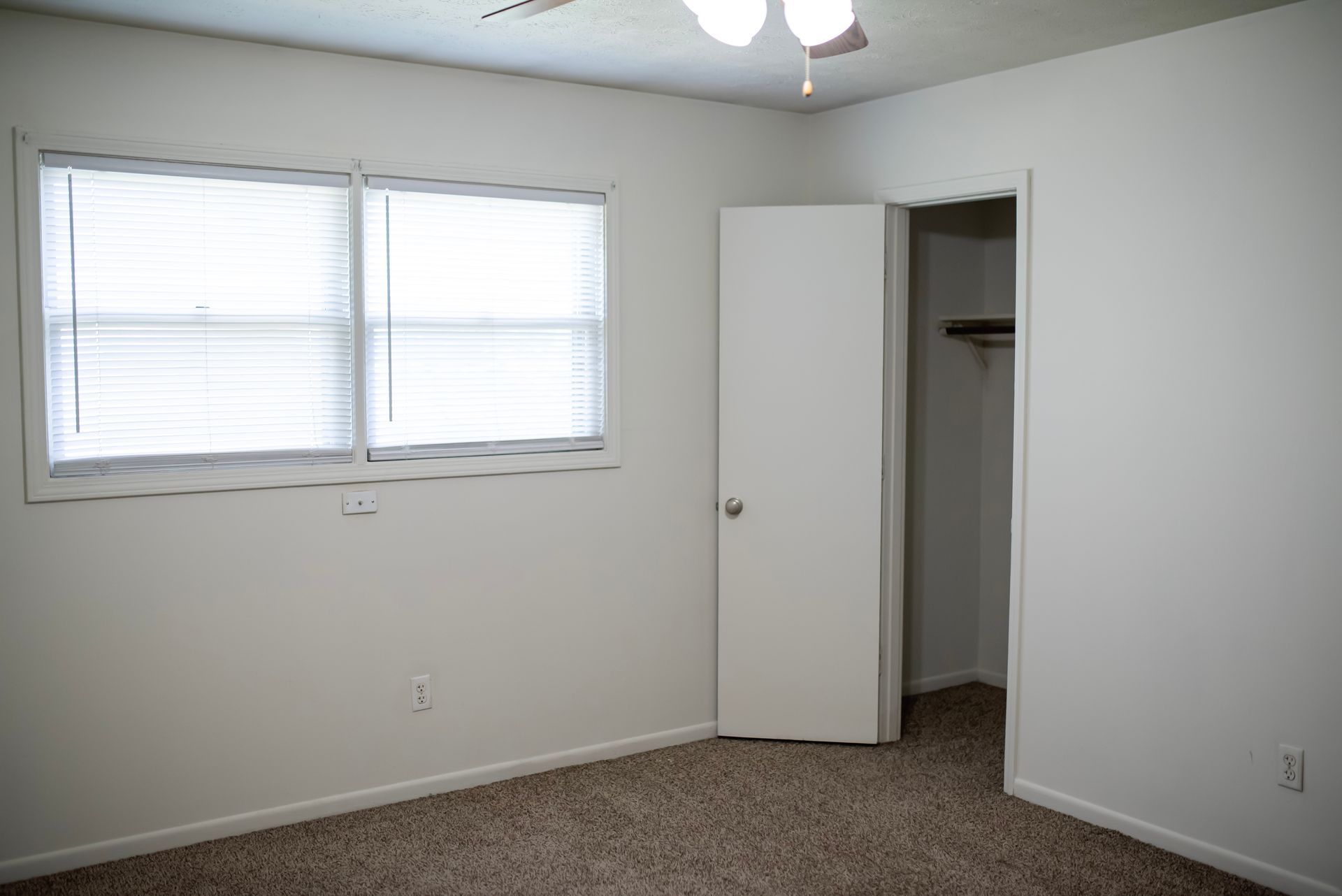 An empty bedroom with a closet and a window.