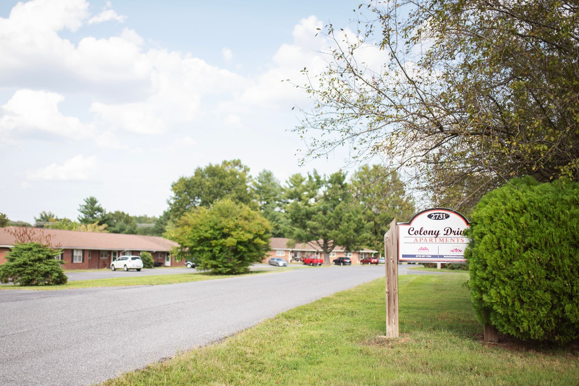 A white sign on a wooden post in front of a house