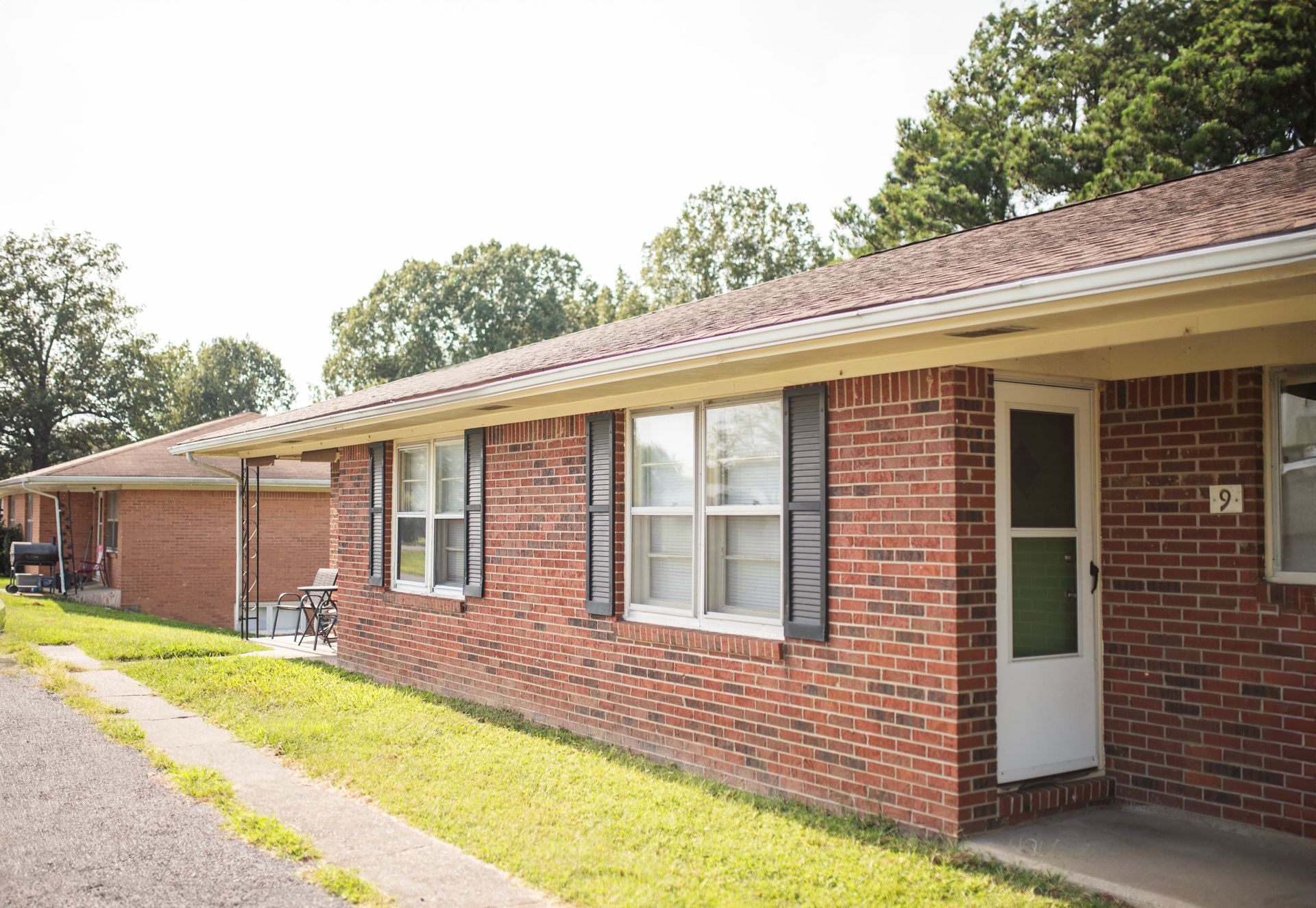 A brick apartment building with a white door and shutters.