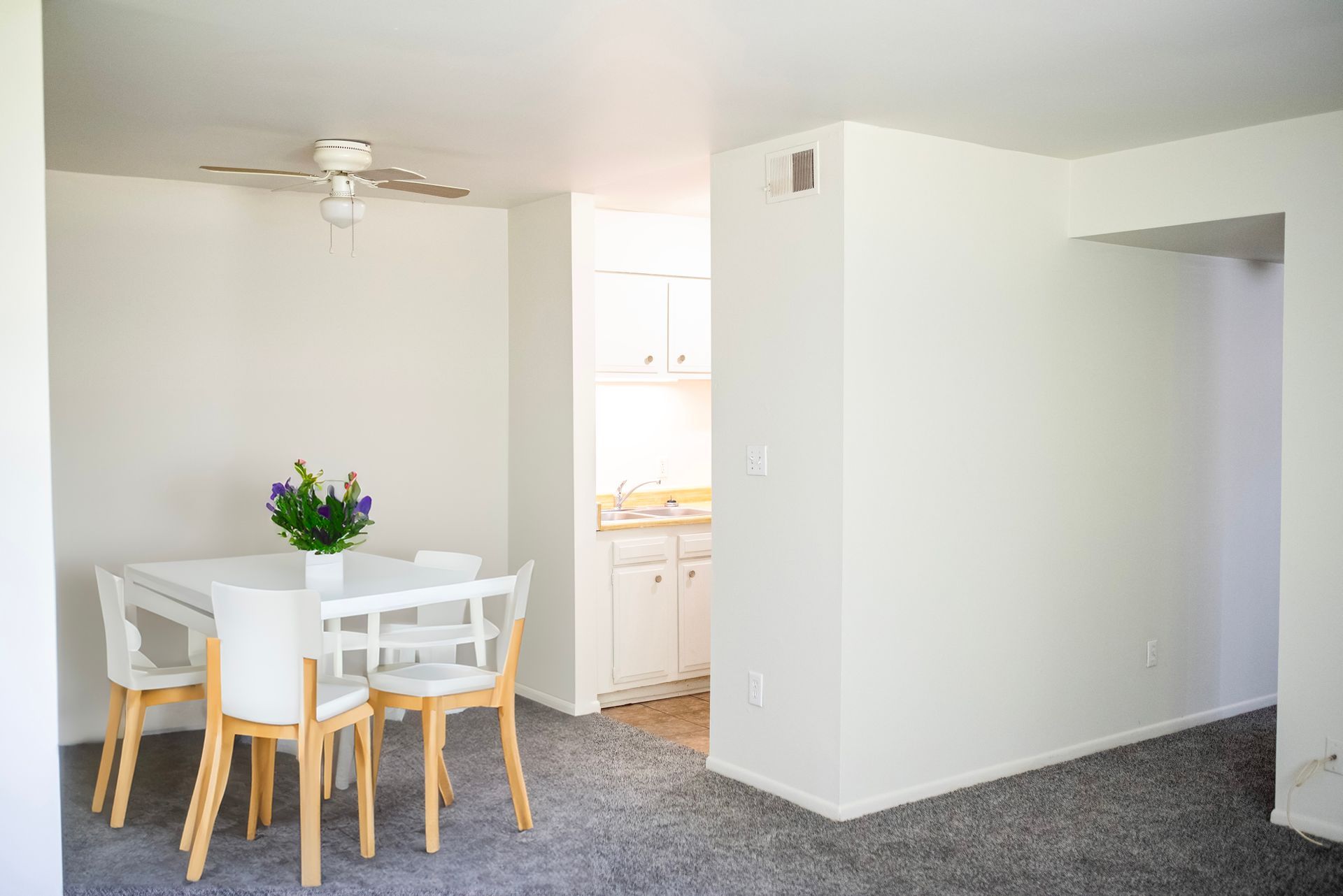 An empty dining room with a table and chairs and a ceiling fan.
