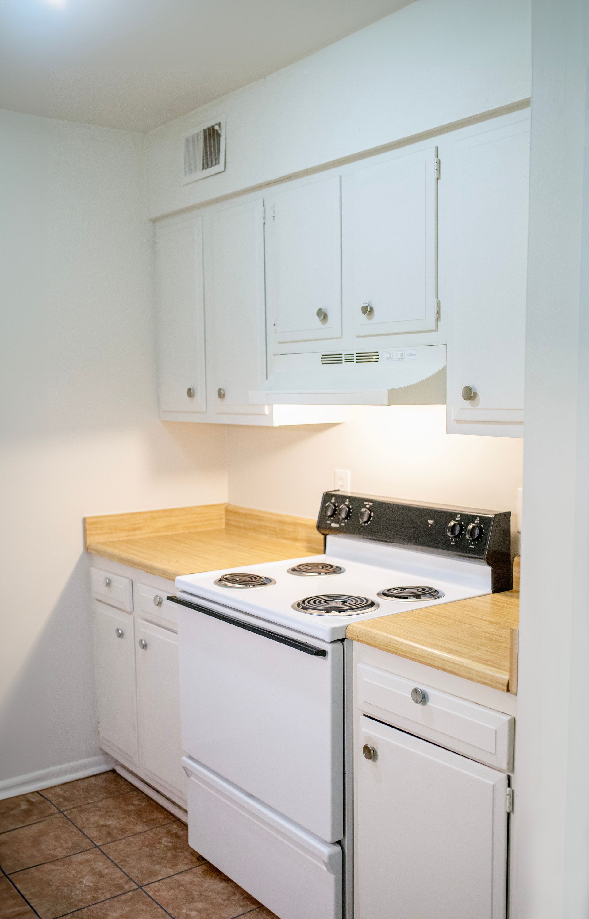 A kitchen with white cabinets , a stove and a dishwasher.