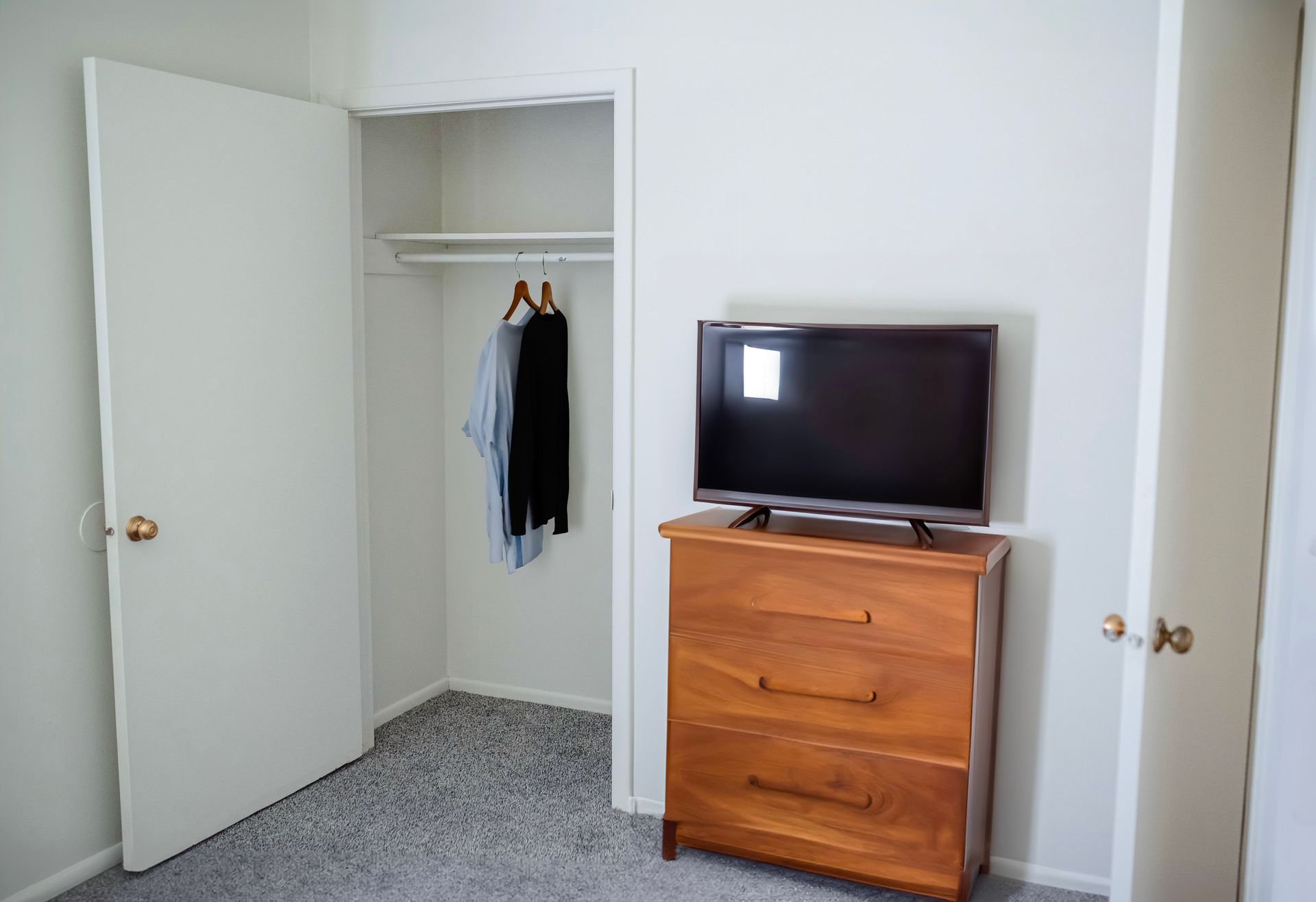 A bedroom with a dresser and a flat screen tv.