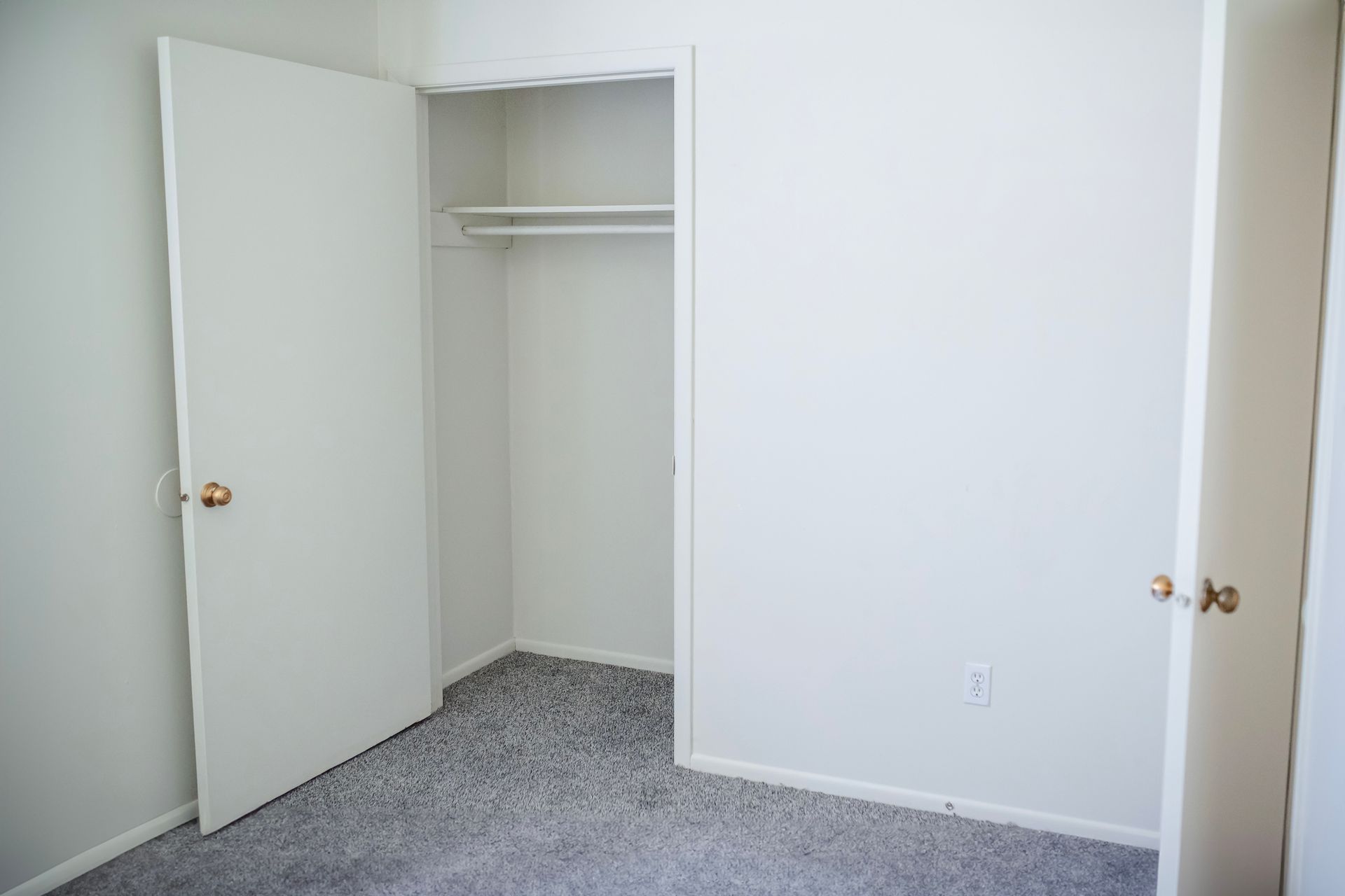 An empty bedroom with a closet and a door open.