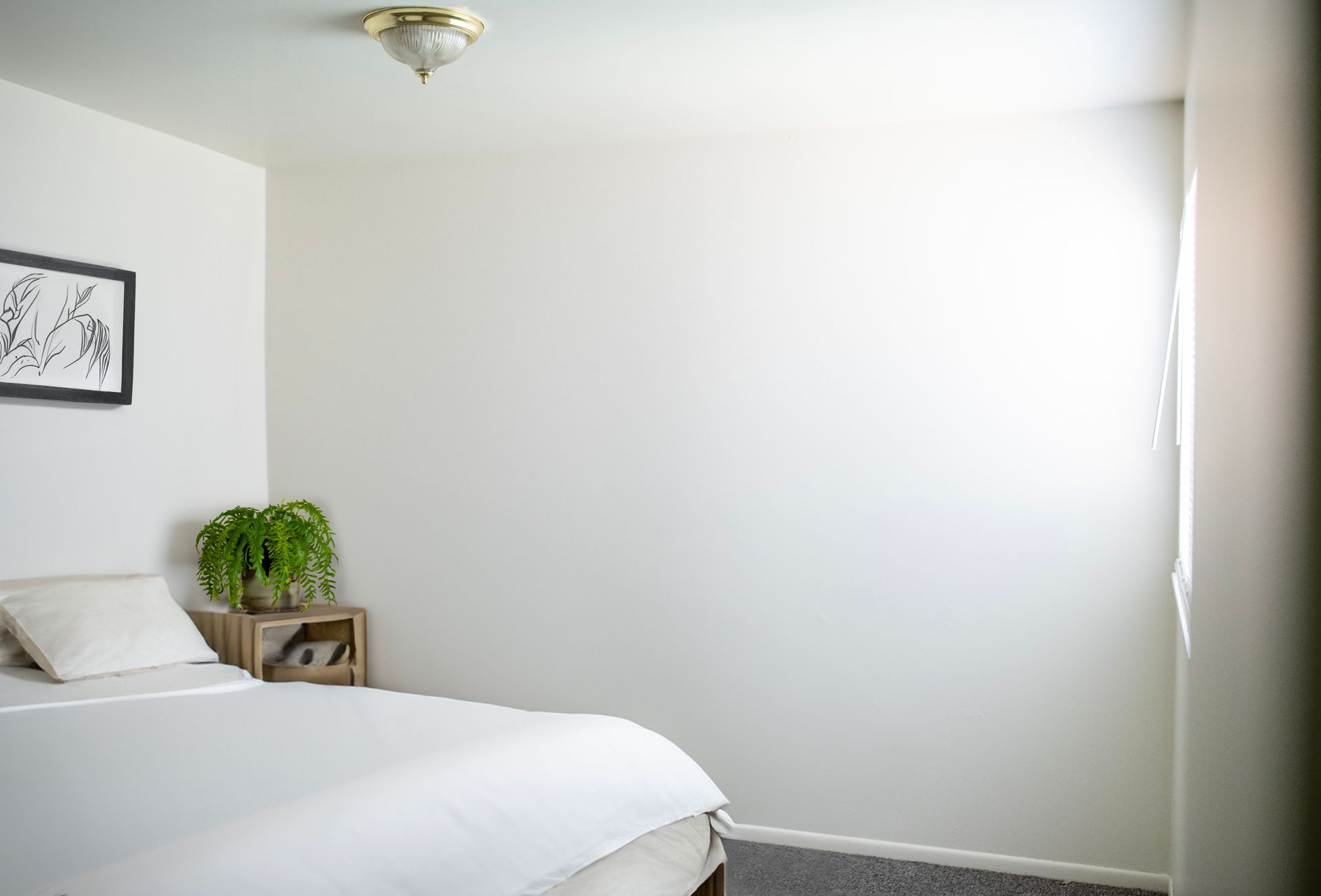 A bedroom with a bed , nightstand , and picture on the wall.