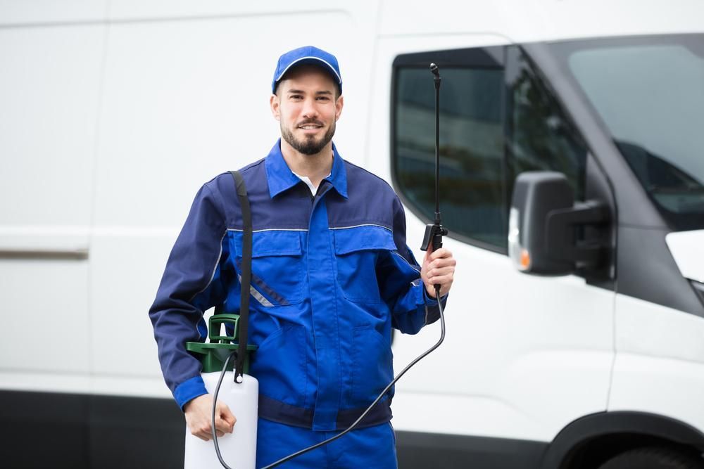 A Man Is Standing In Front Of A Van Holding A Sprayer — X-Terminate Pest Control In Mary Valley, QLD
