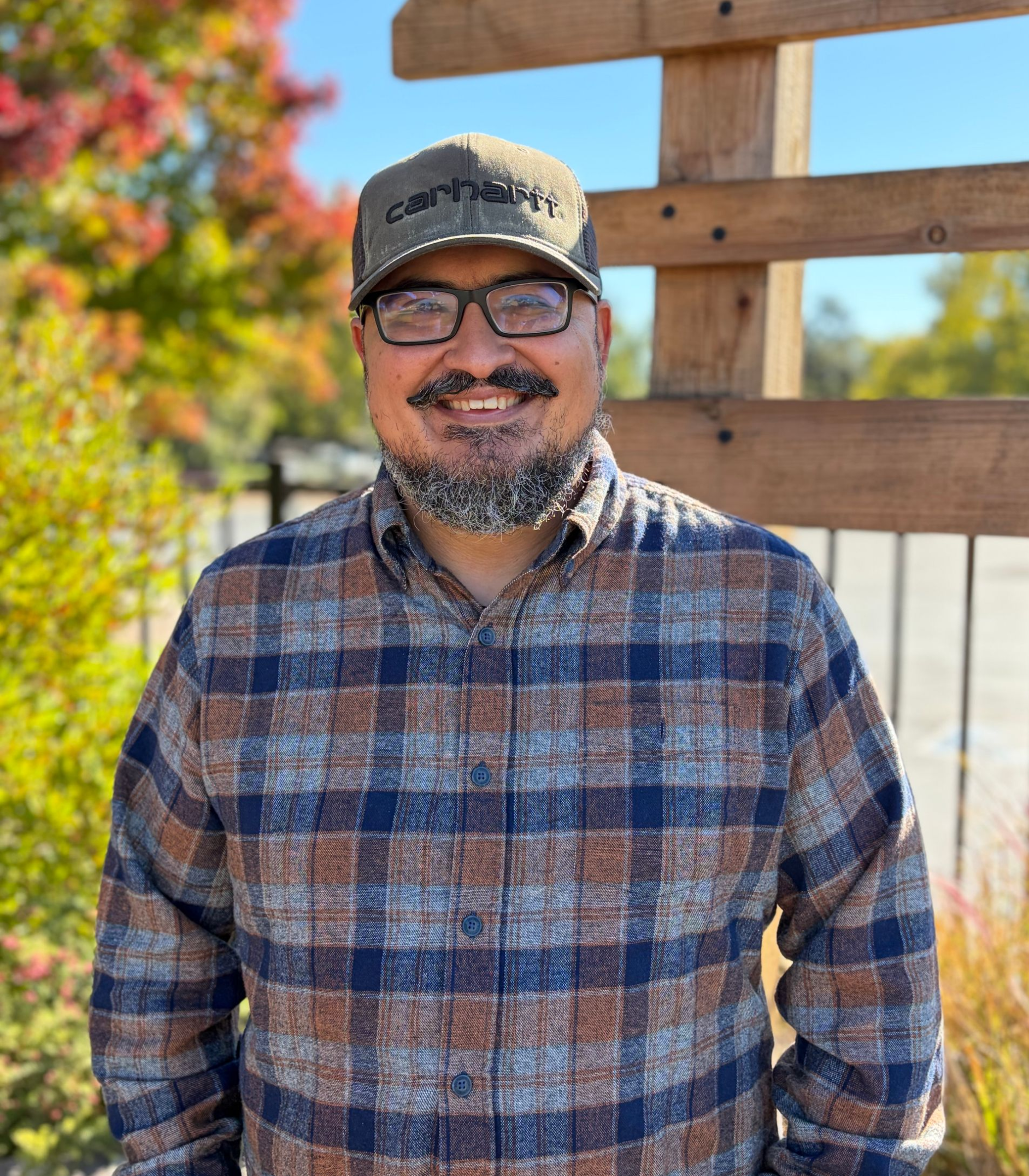A man with long white hair and a beard is wearing a black shirt and smiling.