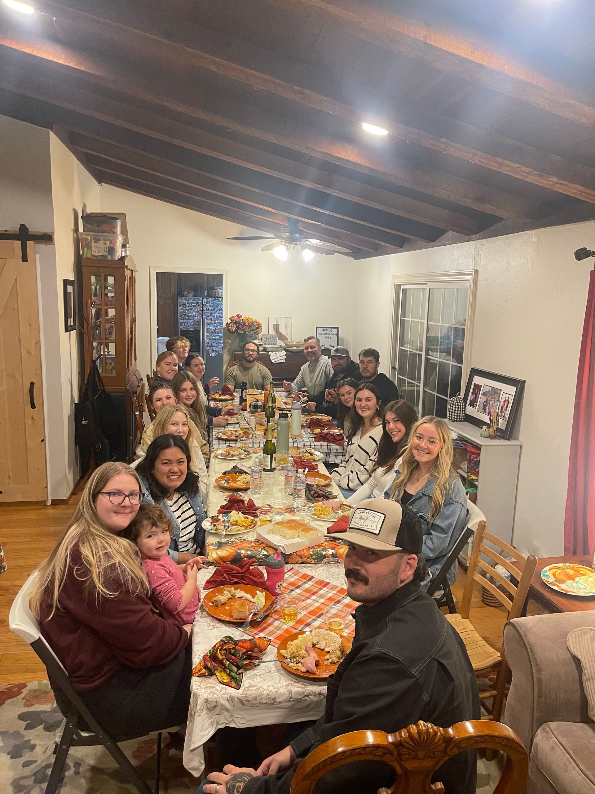 A large group of people are sitting at a long table with plates of food.