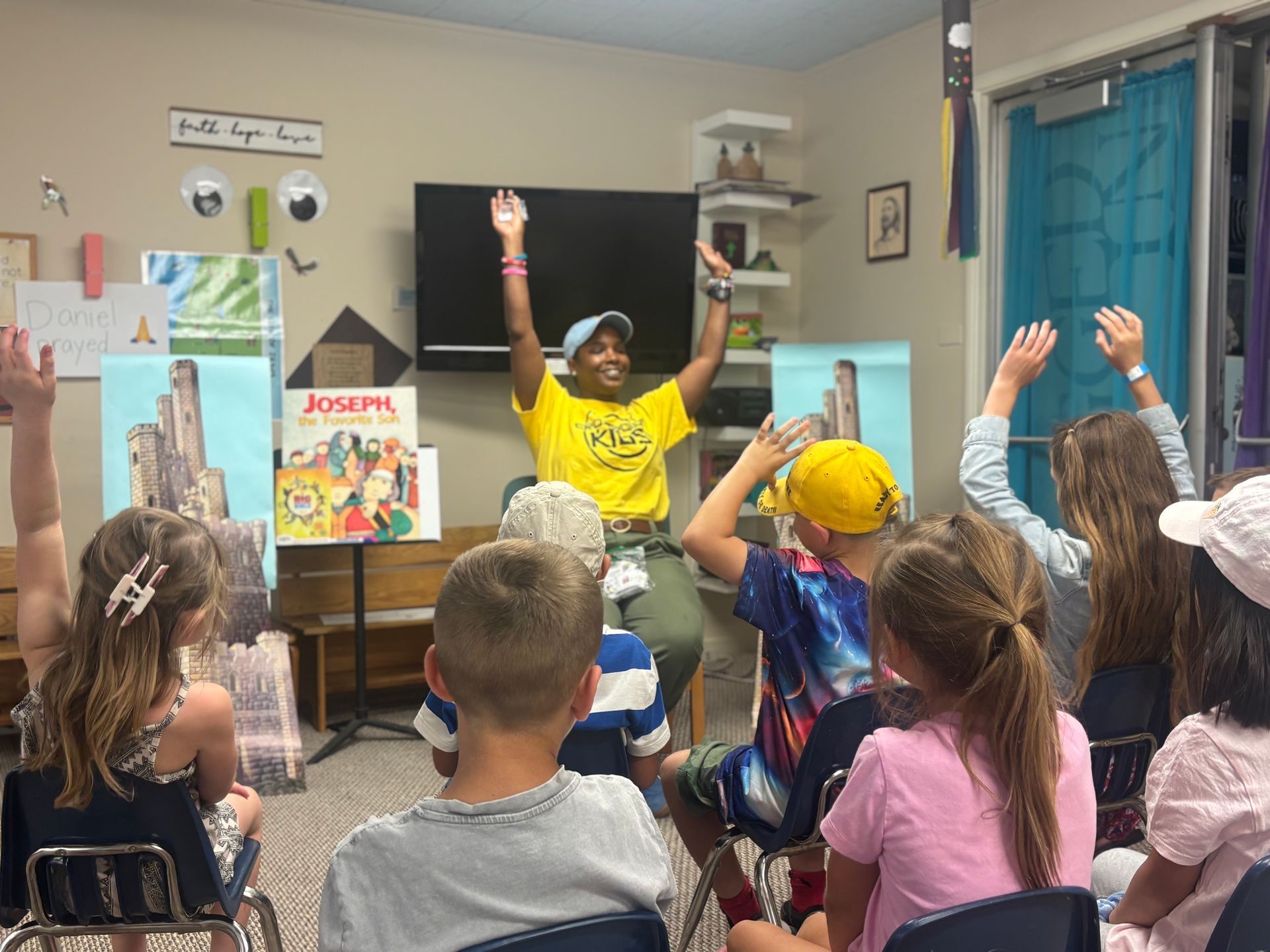 A group of children are standing in a room holding papers.