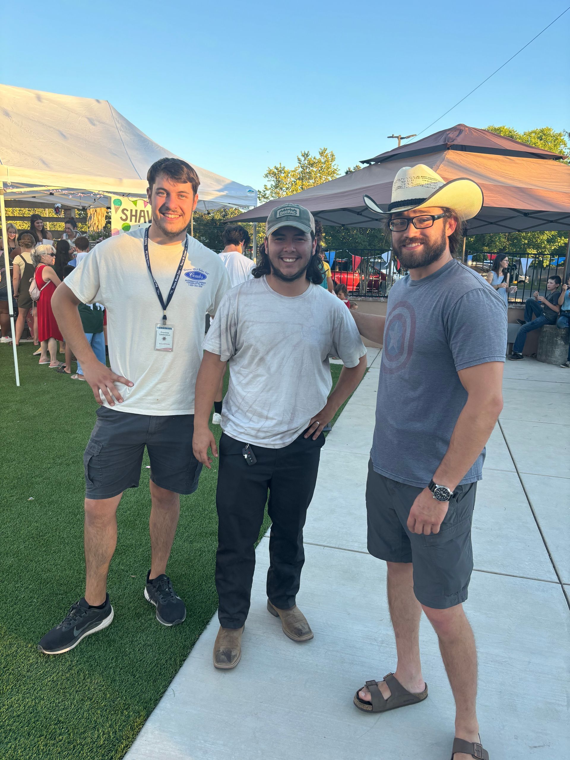 Three men are standing next to each other on a sidewalk.