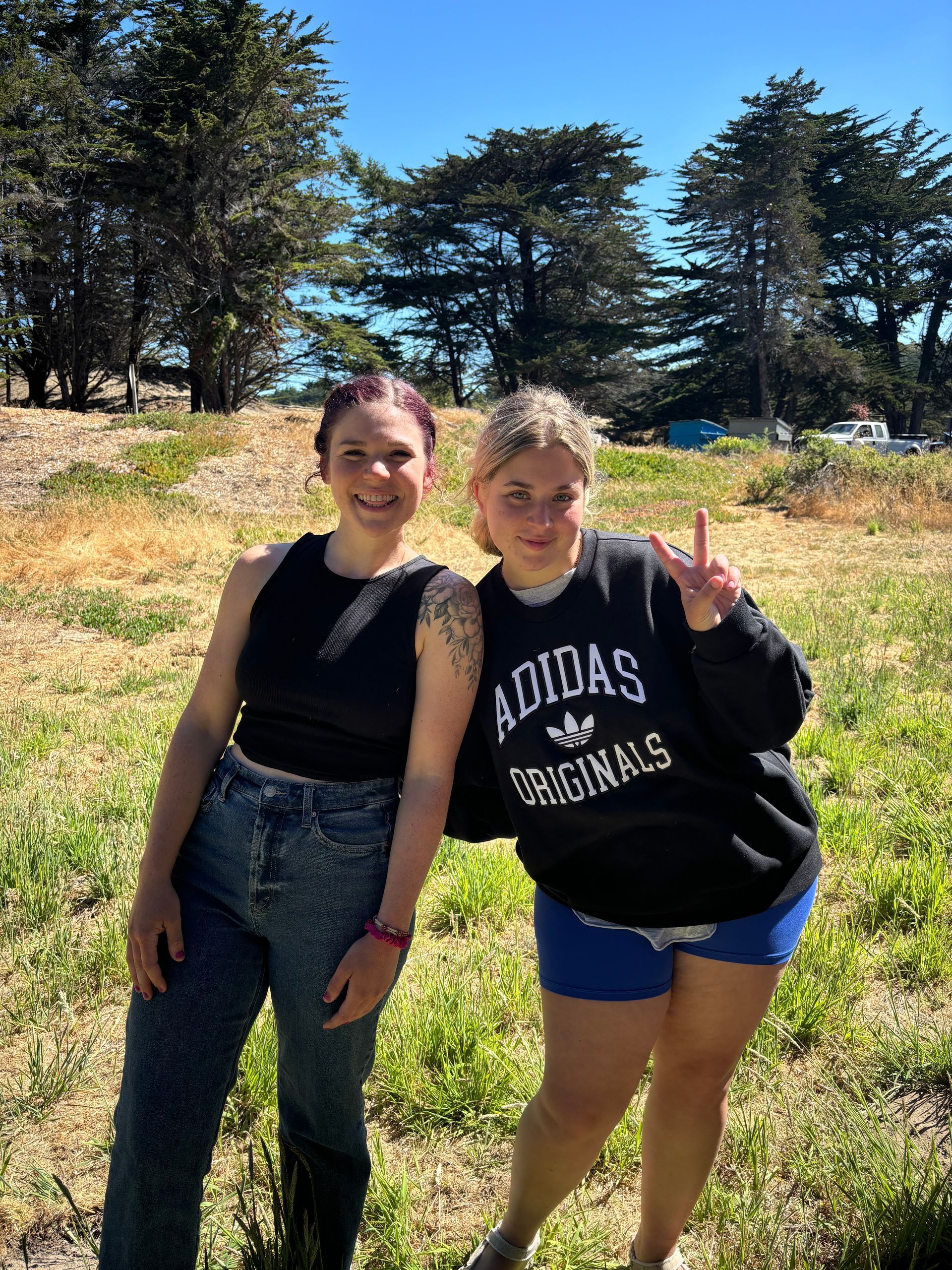 Two women are posing for a picture and one is wearing an adidas originals sweatshirt