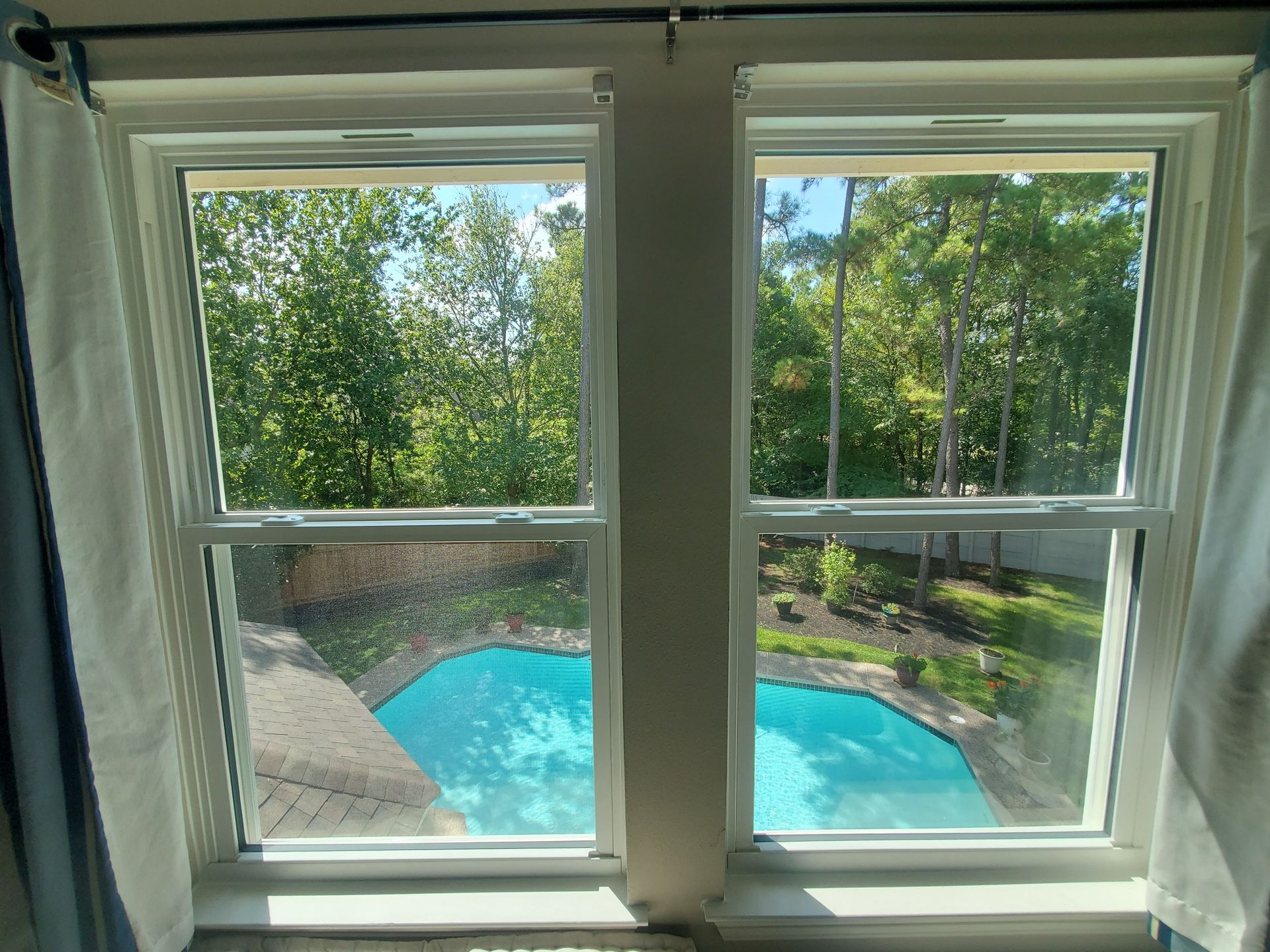 A view of a pool through two windows in a house.