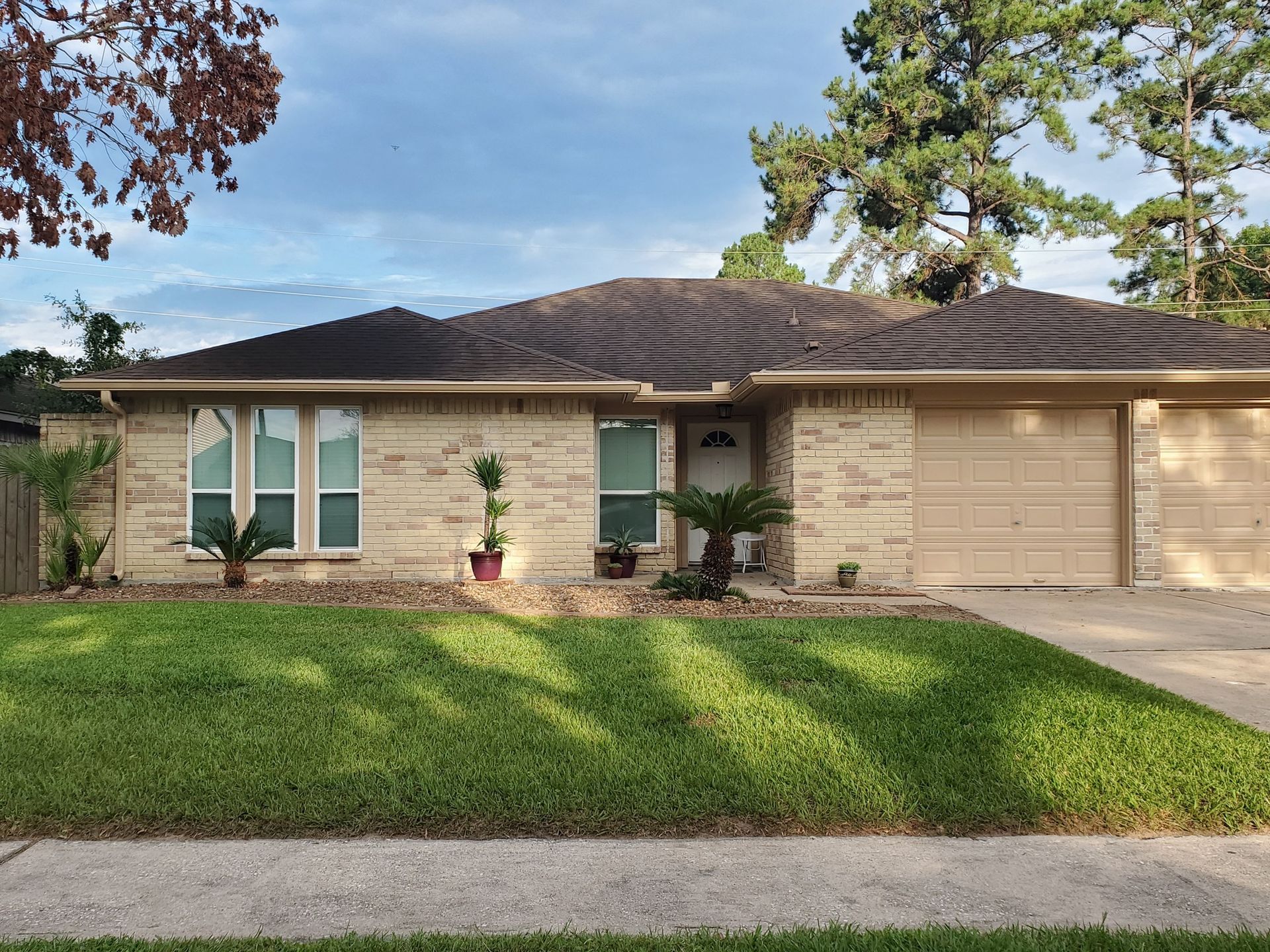 A brick house with two garage doors and a lush green lawn
