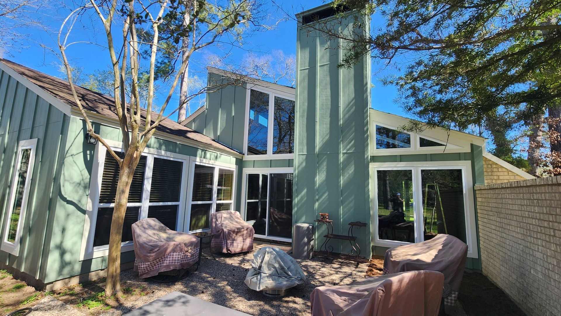 A green house with a lot of windows and a fire pit in the backyard.