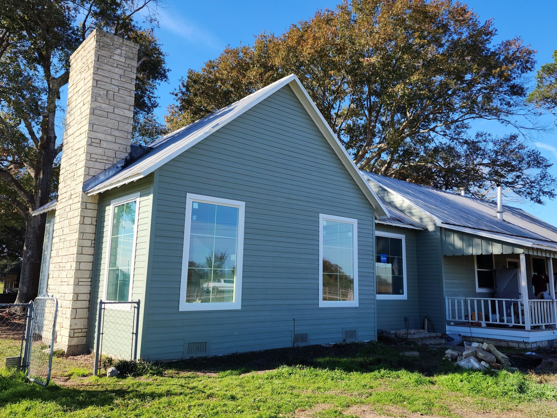 A house with a chimney on the side of it is sitting on top of a lush green field.