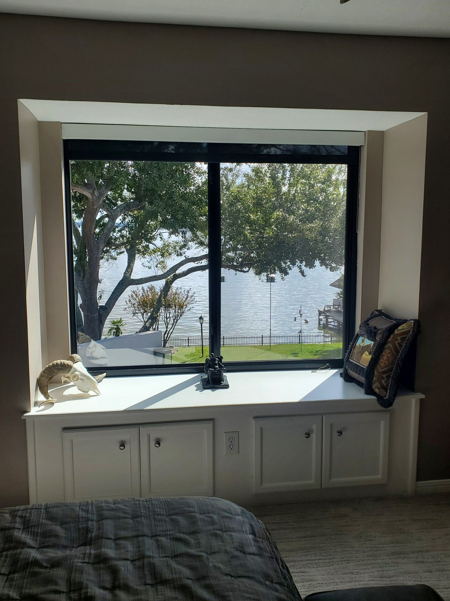 A bedroom with a large window with a view of a lake.