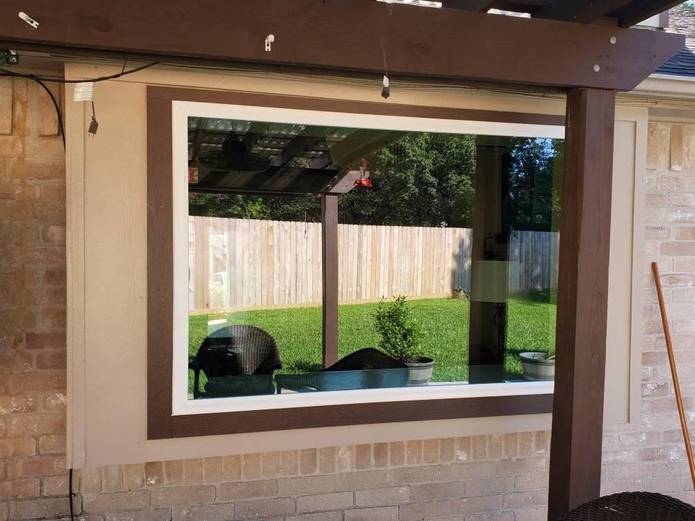 A large window on the side of a house with a fence in the background