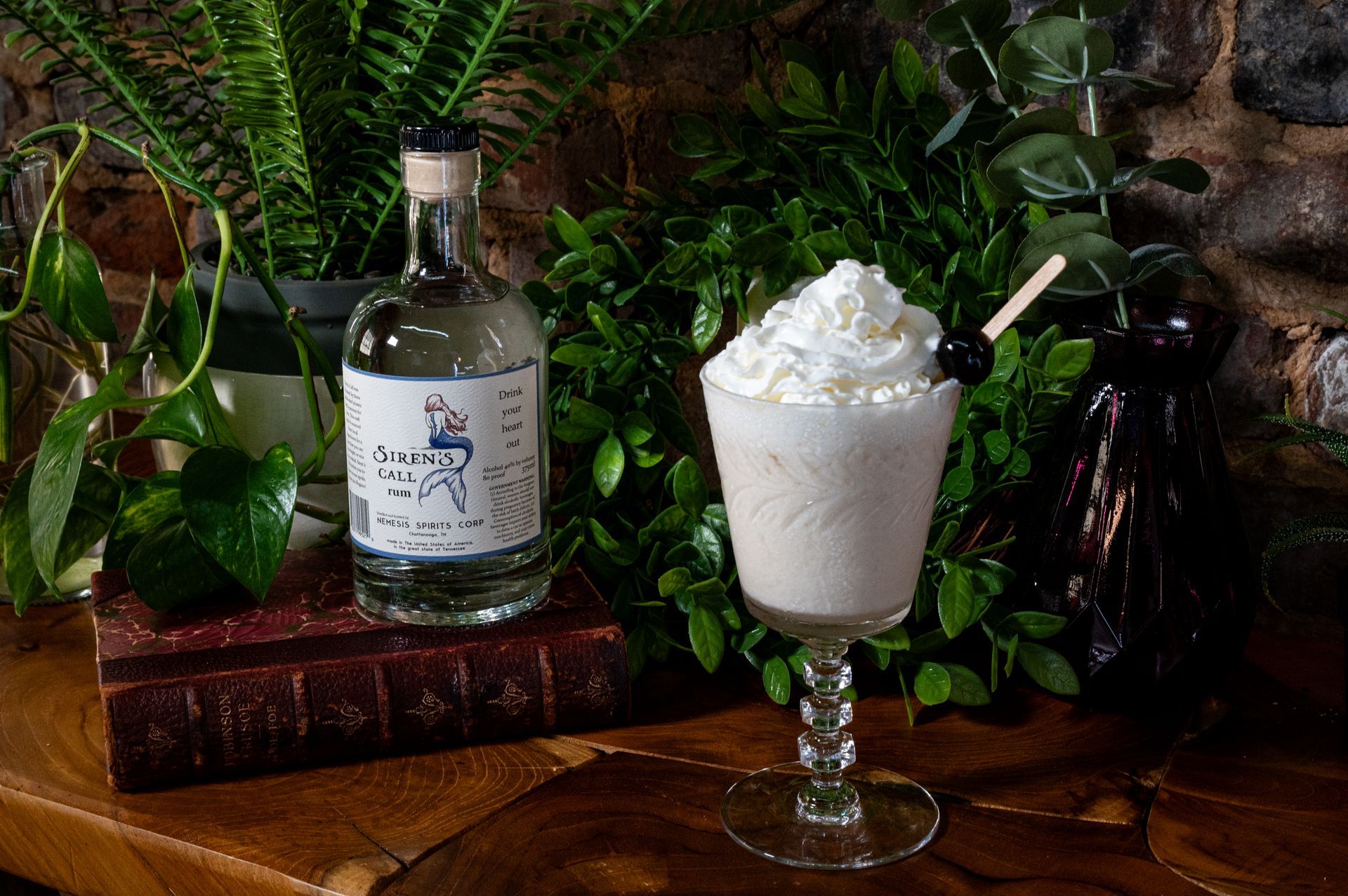 A bottle of liquor and a glass of milkshake on a wooden table.