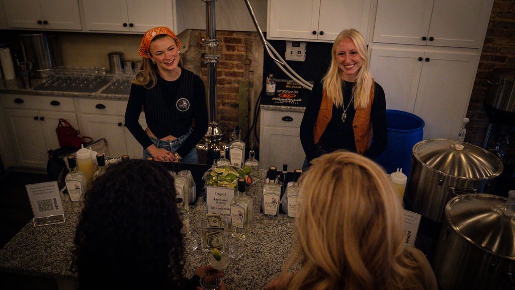 A group of women are standing around a counter in a kitchen.
