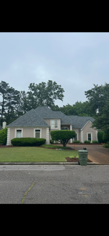 Hand turning a dial on a white water heater mounted on a gray wall. Silver pipes and a power cord are visible.