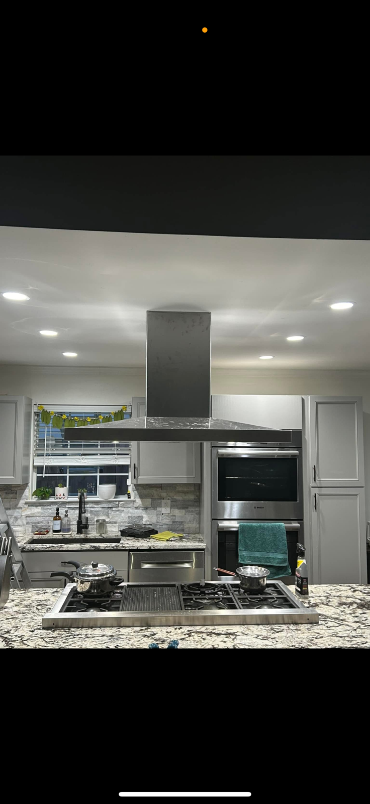 A person in blue overalls kneels, installing light-colored laminate flooring with tools scattered around.
