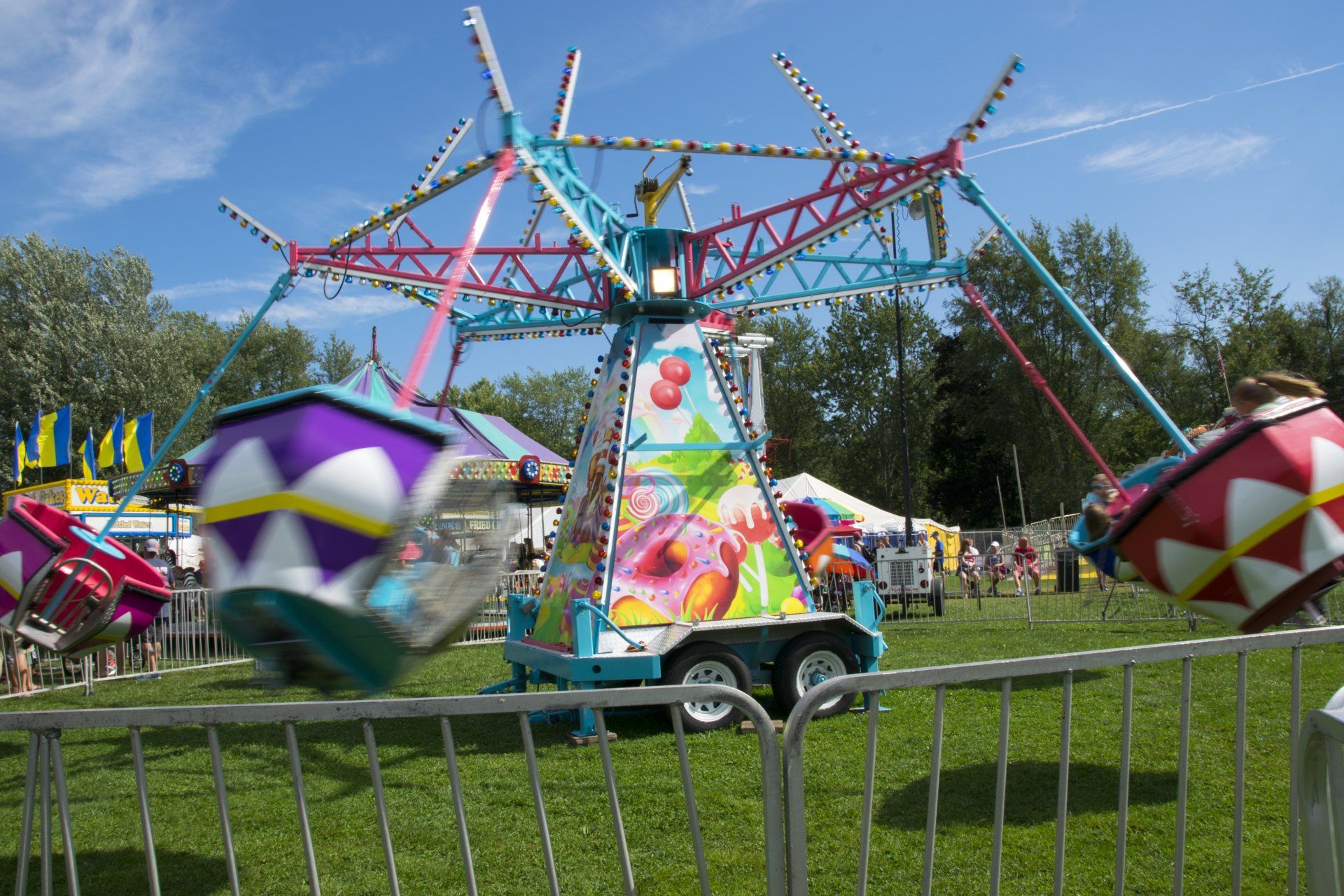 A carnival ride is behind a metal fence