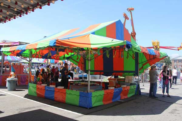 A colorful tent at a carnival with people standing around it