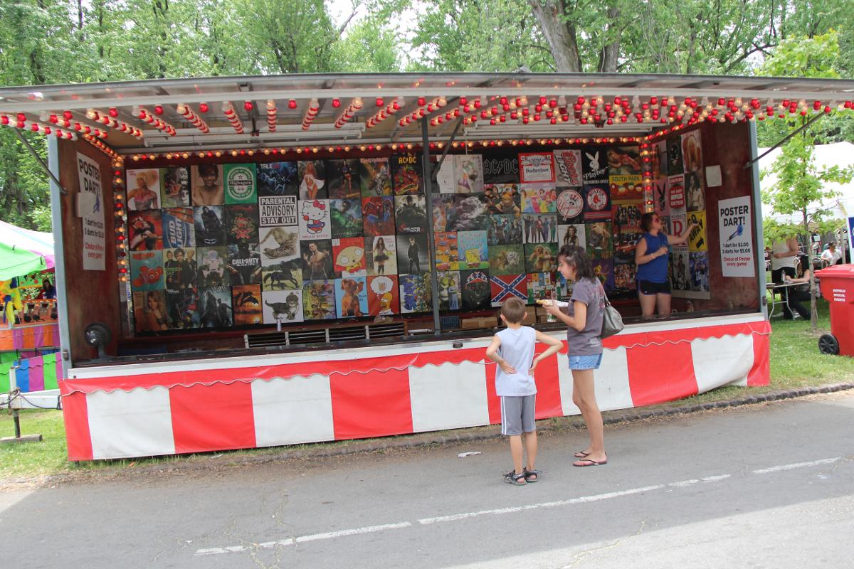 A girl and a boy are standing in front of a carnival booth