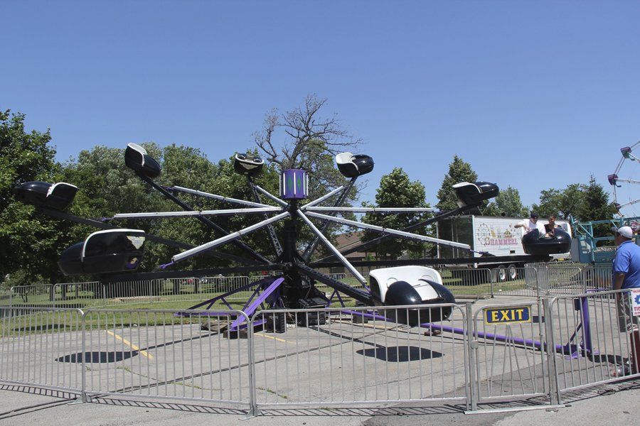 A carnival ride is behind a fence that says caution