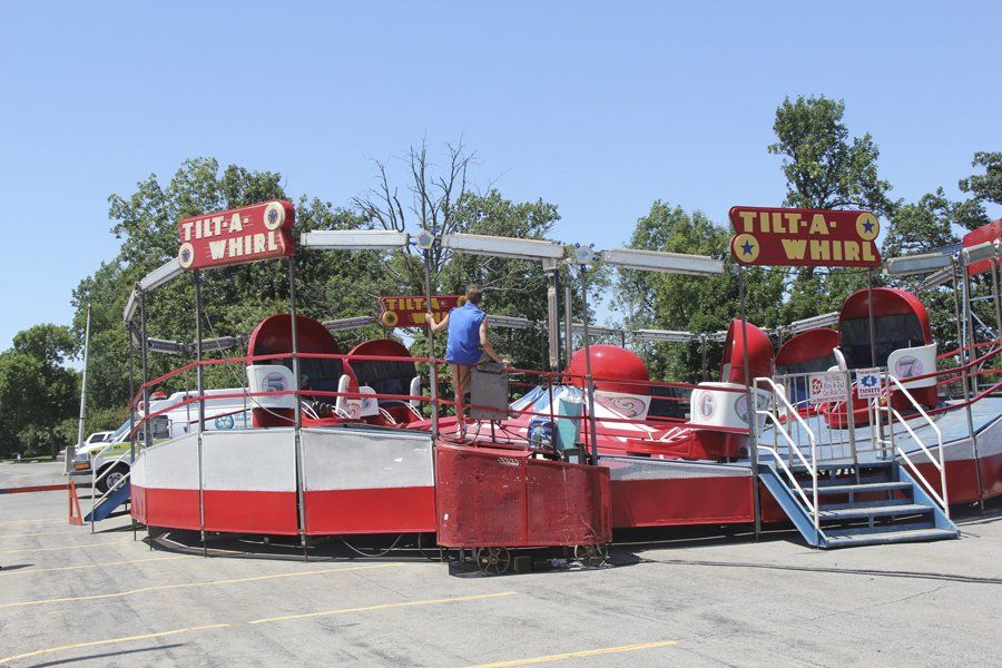 A man stands on top of a tilt-a-whirl ride