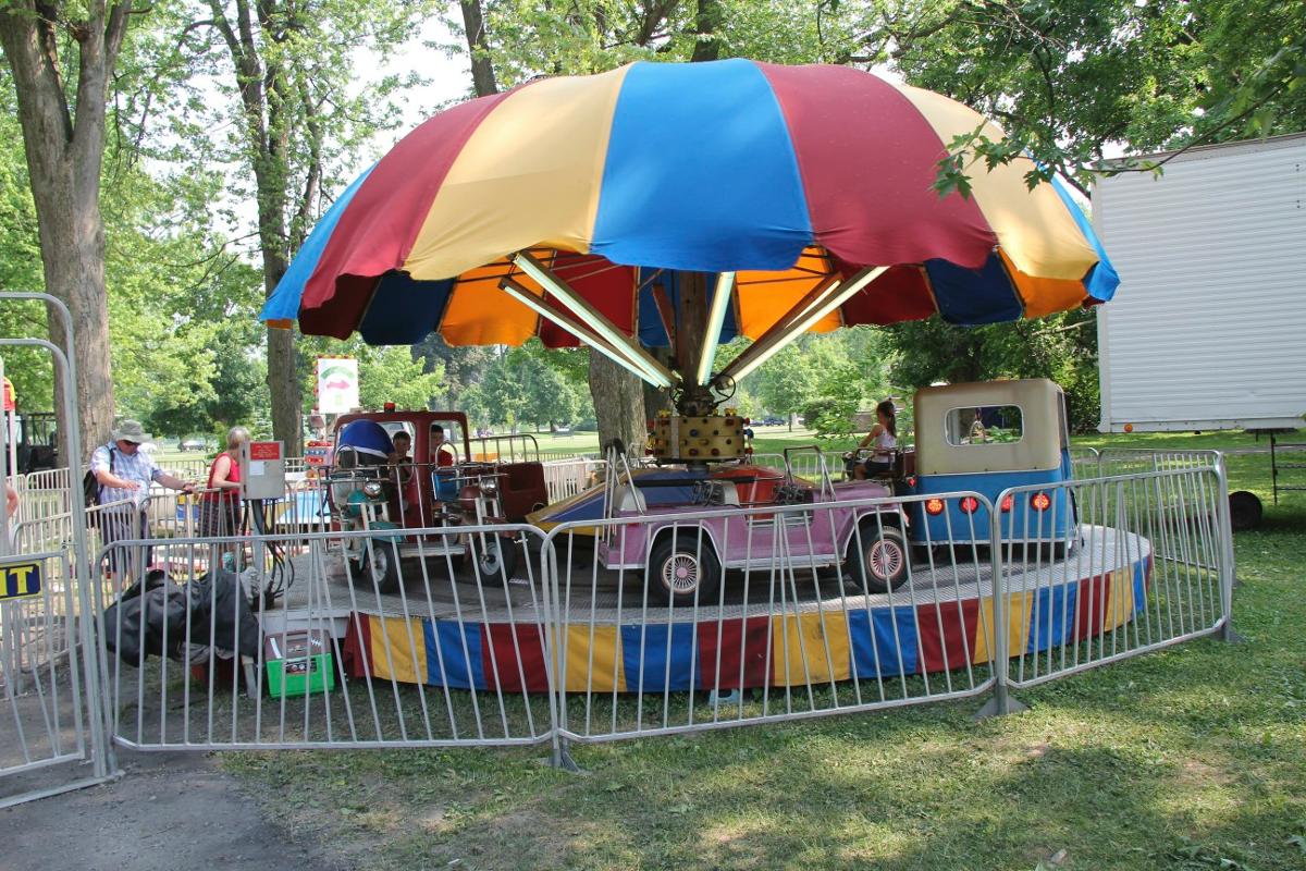 A merry go round in a park with a colorful umbrella