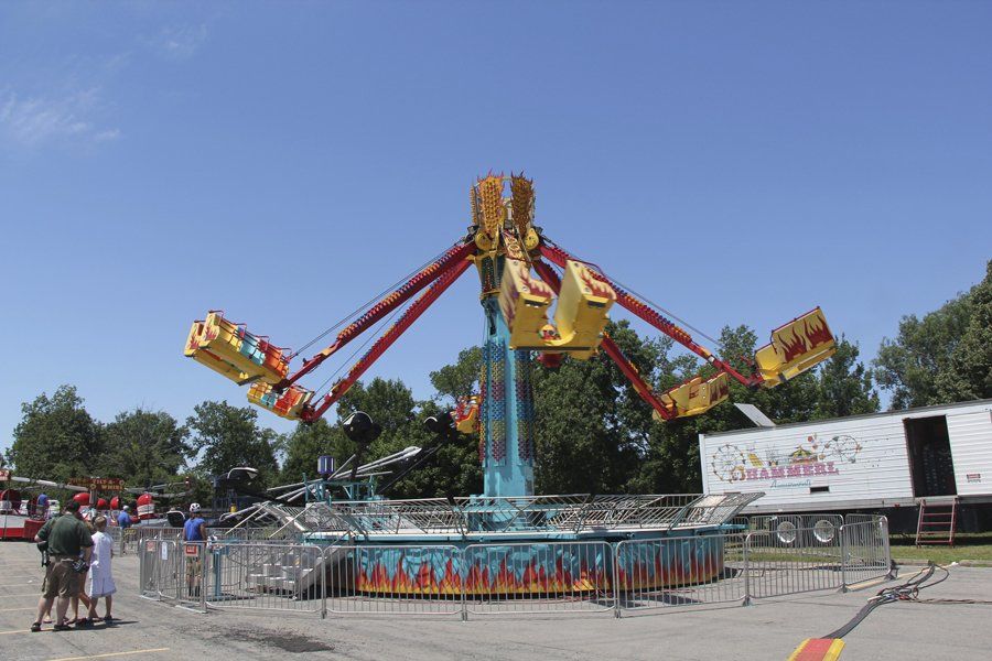A carnival ride with a trailer behind it that says steam roller