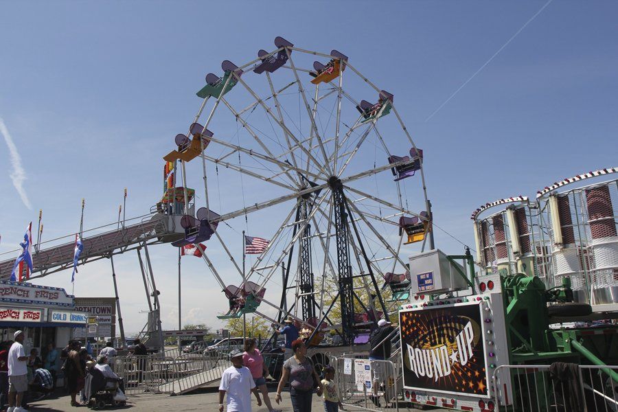 A ferris wheel at a carnival with people walking around