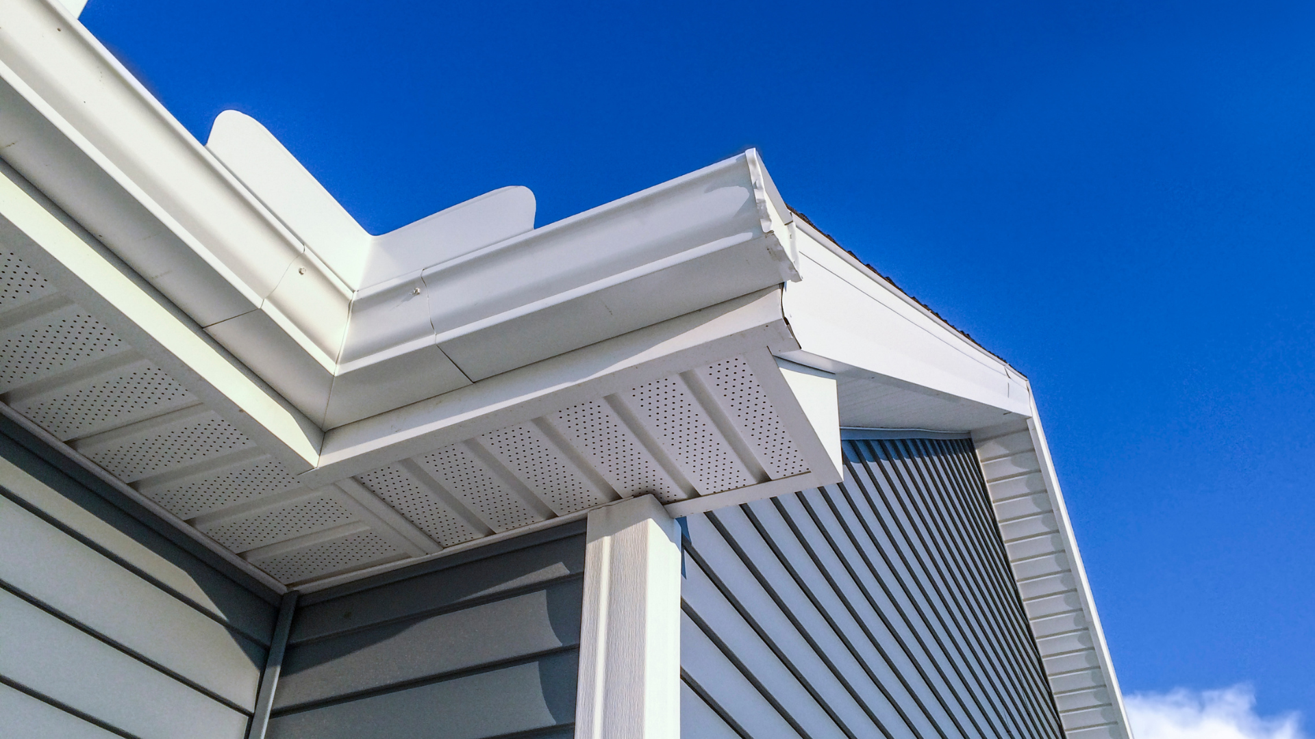 White eaves and gutters on a building against a bright blue sky.
