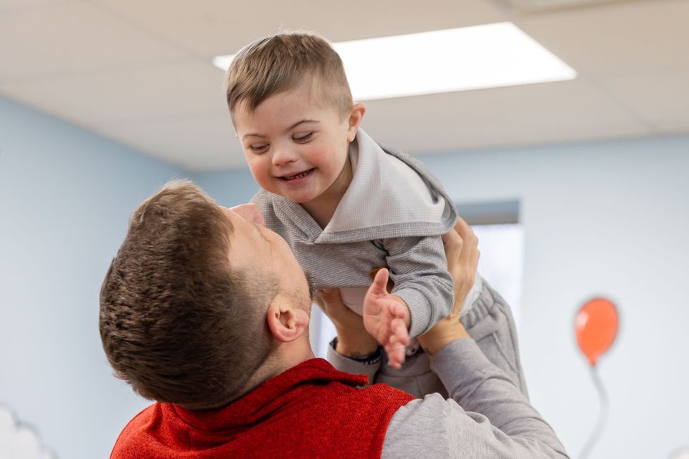 A man is holding a little boy in the air.