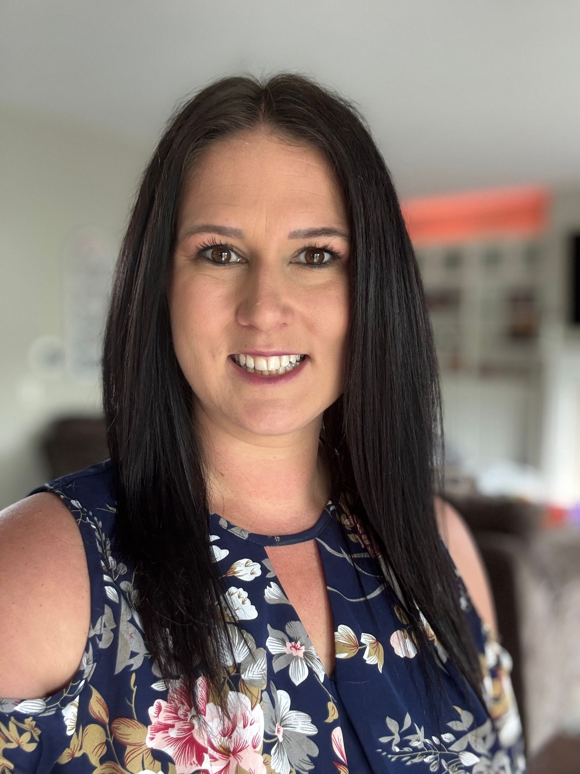 A woman in a blue floral shirt is smiling for the camera.