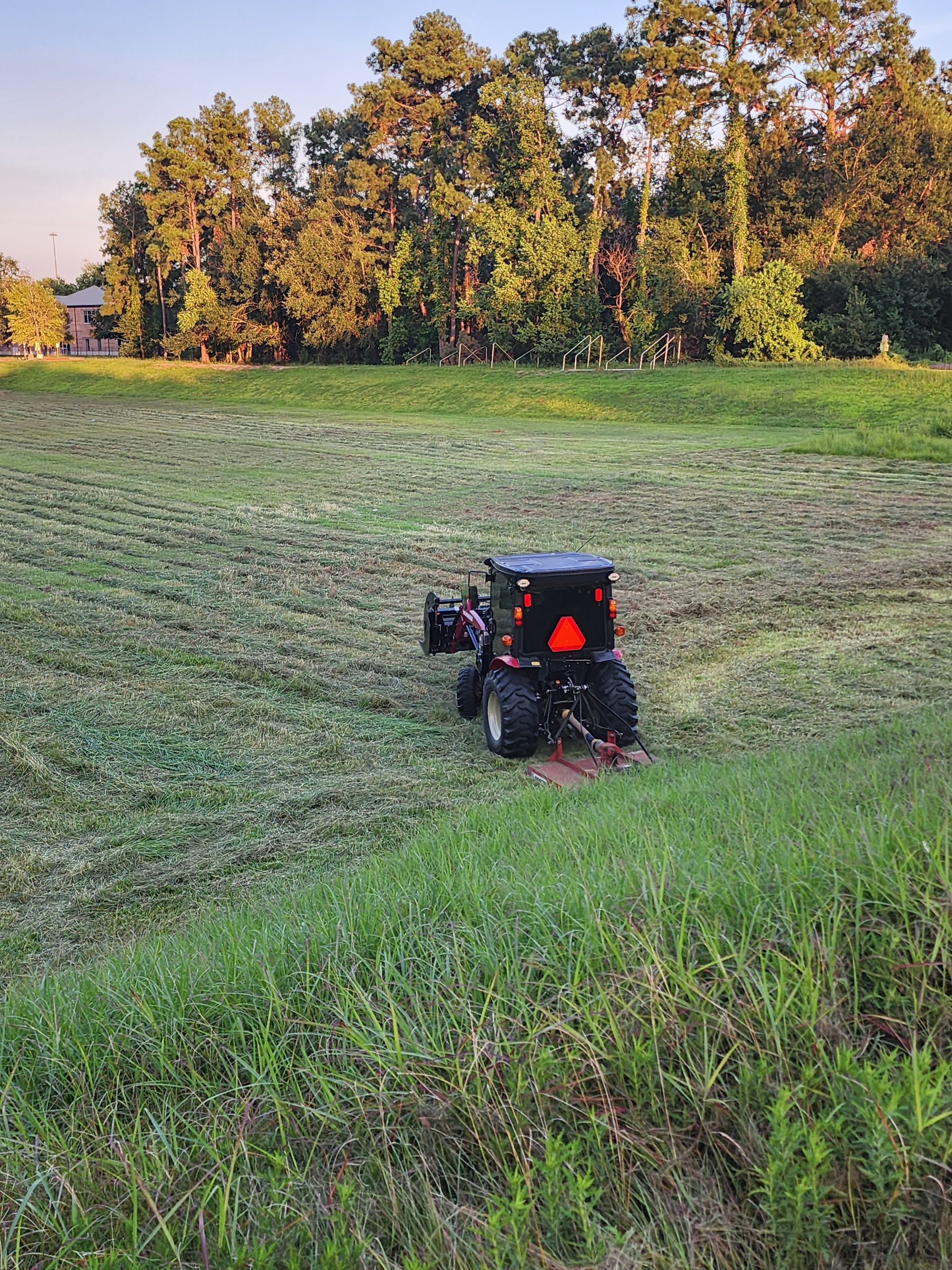 A large grassy field with trees in the background.
