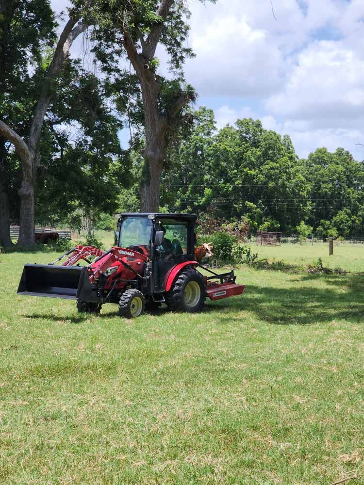 A red tractor is parked in a grassy field.