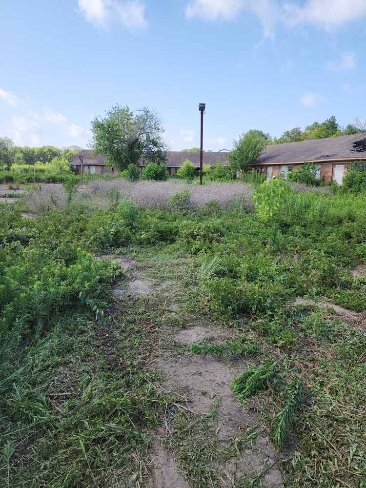An aerial view of a lush green field with a house in the background.