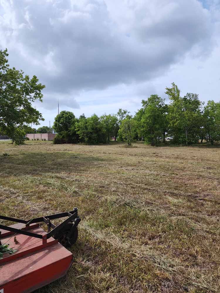 A lawn mower is sitting in the middle of a field.