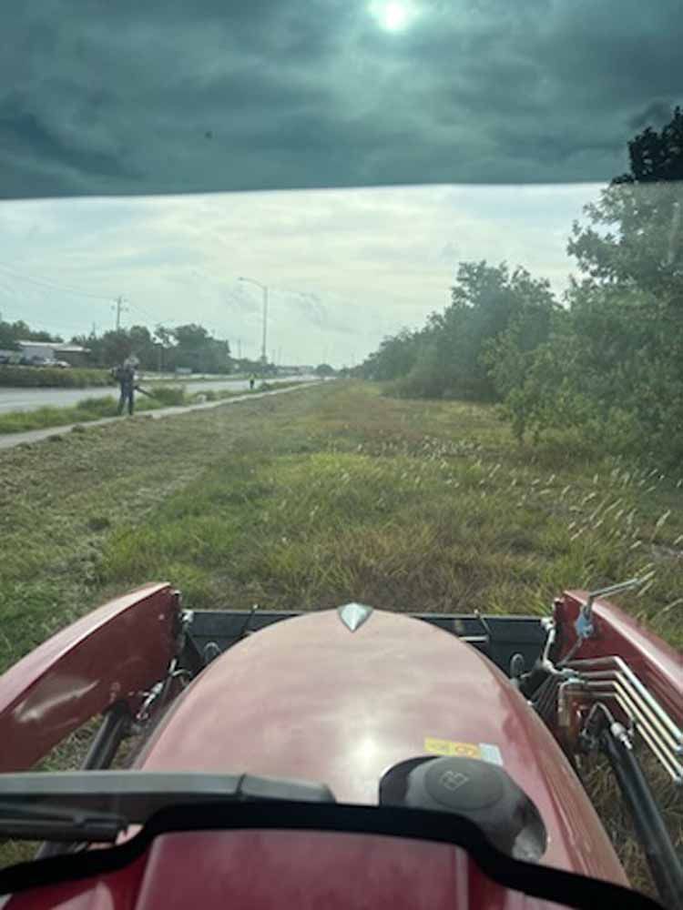 A red tractor is driving down a grassy road.